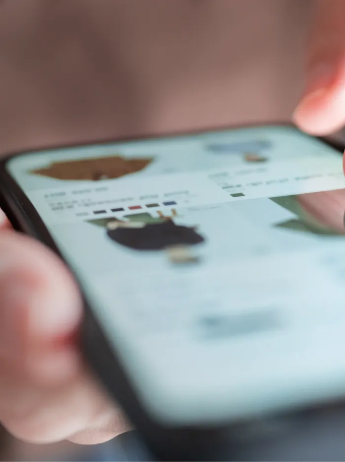 Close-up of a person browsing clothing items on a smartphone screen.