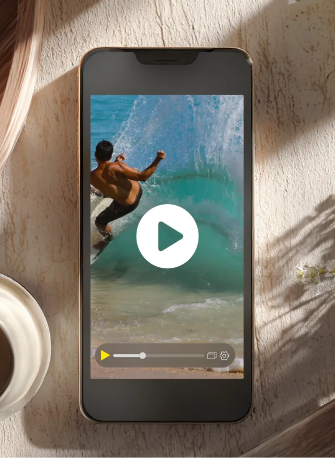 Smartphone displaying paused video of a shirtless man surfing on a wave.