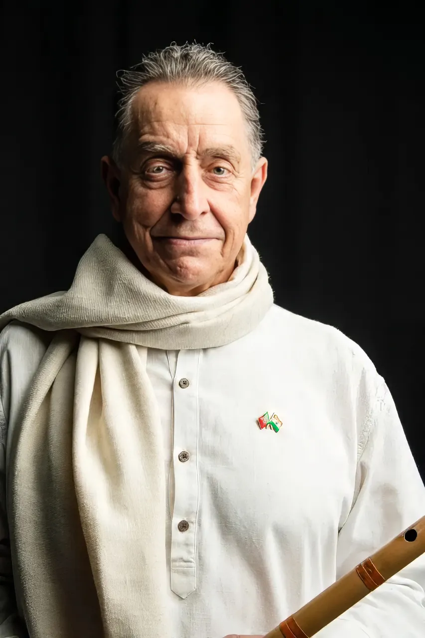 Man with white clothes, a flute in his hands, and in a dark background.