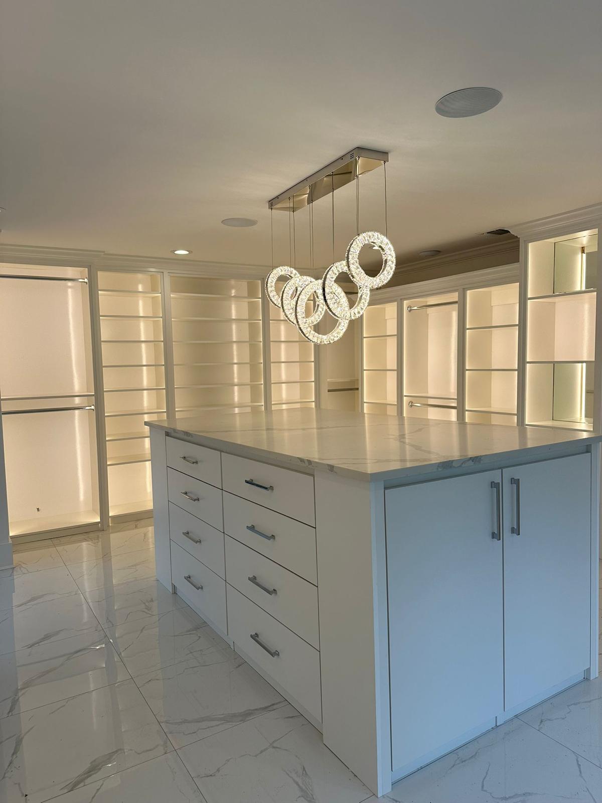 Luxurious custom walk-in closet in New Jersey with white built-in cabinetry, open shelves, and large island