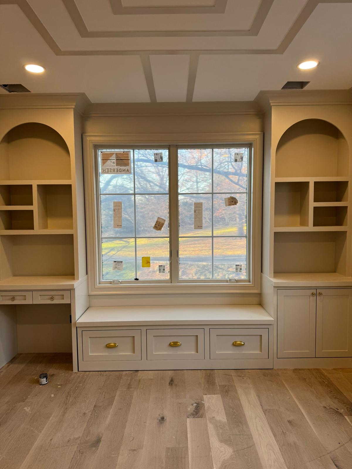 Light-colored built-in cabinetry with a window bench and a coffered ceiling in a New Jersey room.