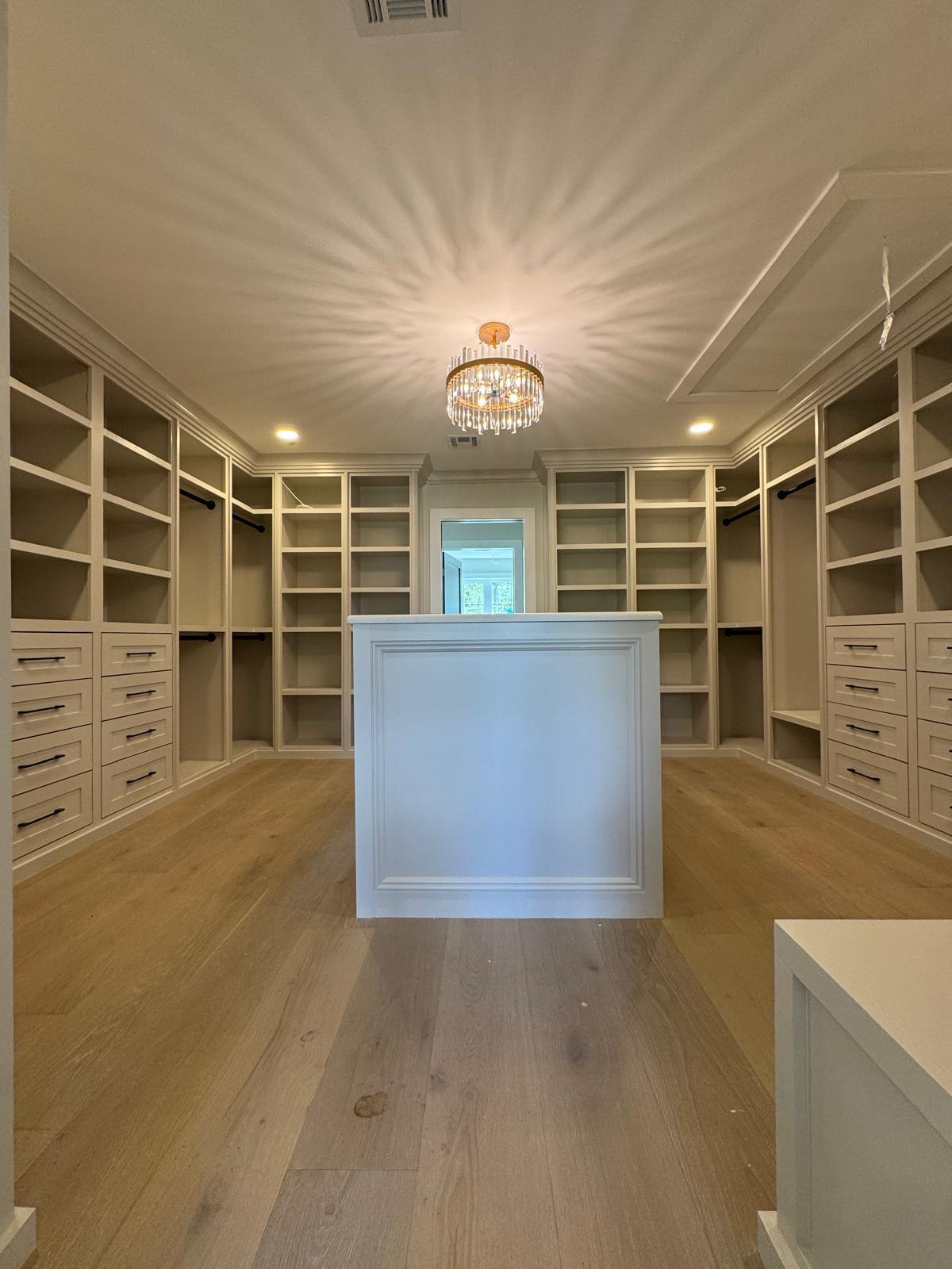 Custom walk-in closet in a New Jersey home featuring built-in cabinetry, open shelving, drawers, and a central island.