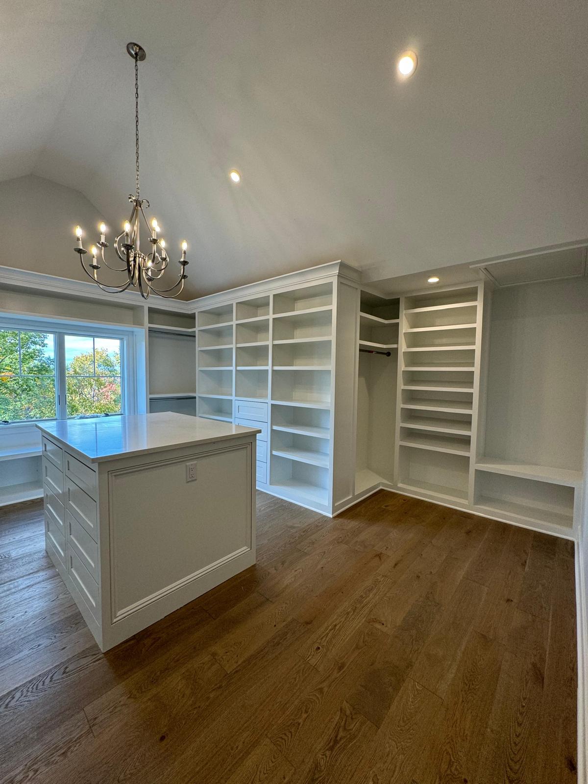 Custom white walk-in closet with built-in shelving, drawers, and center island in a New Jersey home
