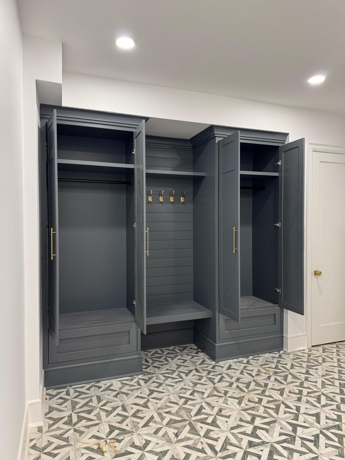 Dark gray built-in mudroom unit with bench, coat hooks, and storage cabinets in a New Jersey entryway