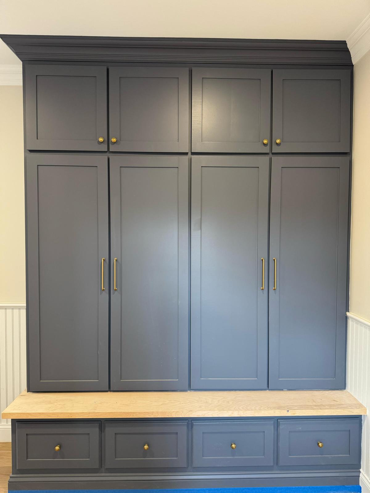 Custom dark gray mudroom unit with wood bench, drawers, and cabinet doors, flanked by white beadboard wainscoting in NJ