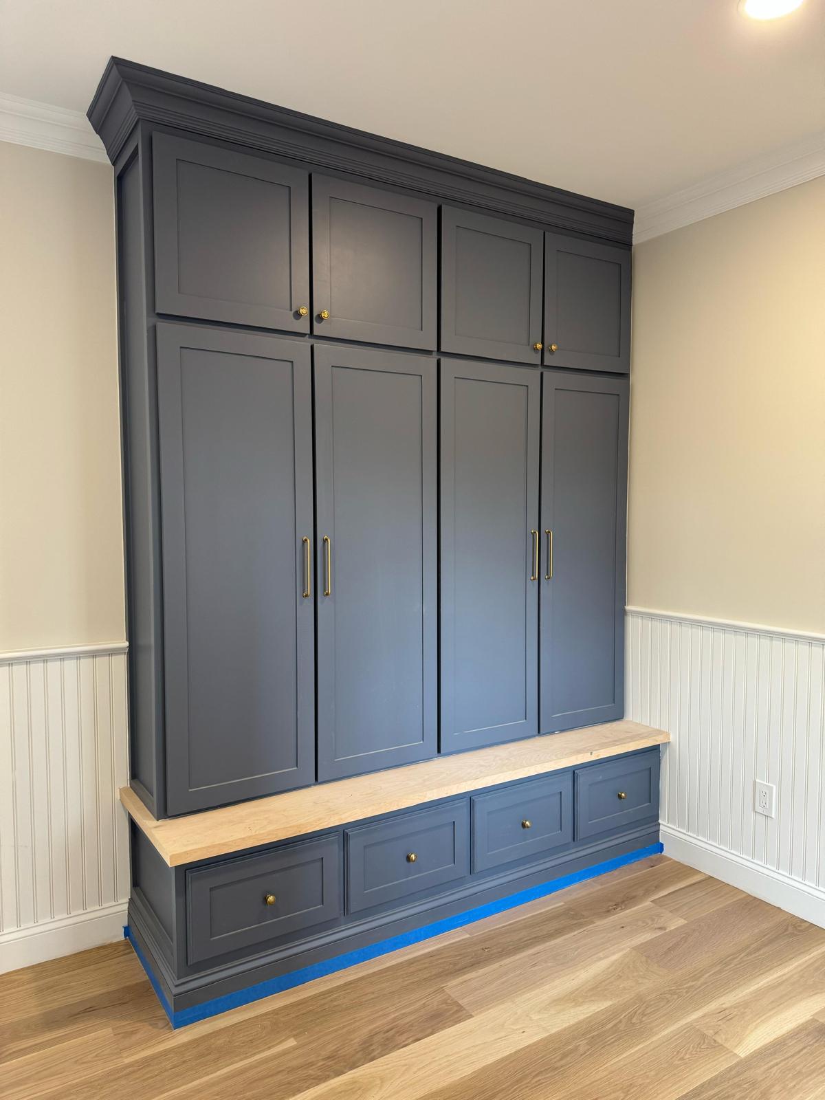 Dark gray built-in mudroom unit with a wood bench and drawers, flanked by white beadboard wainscoting in an NJ entryway.