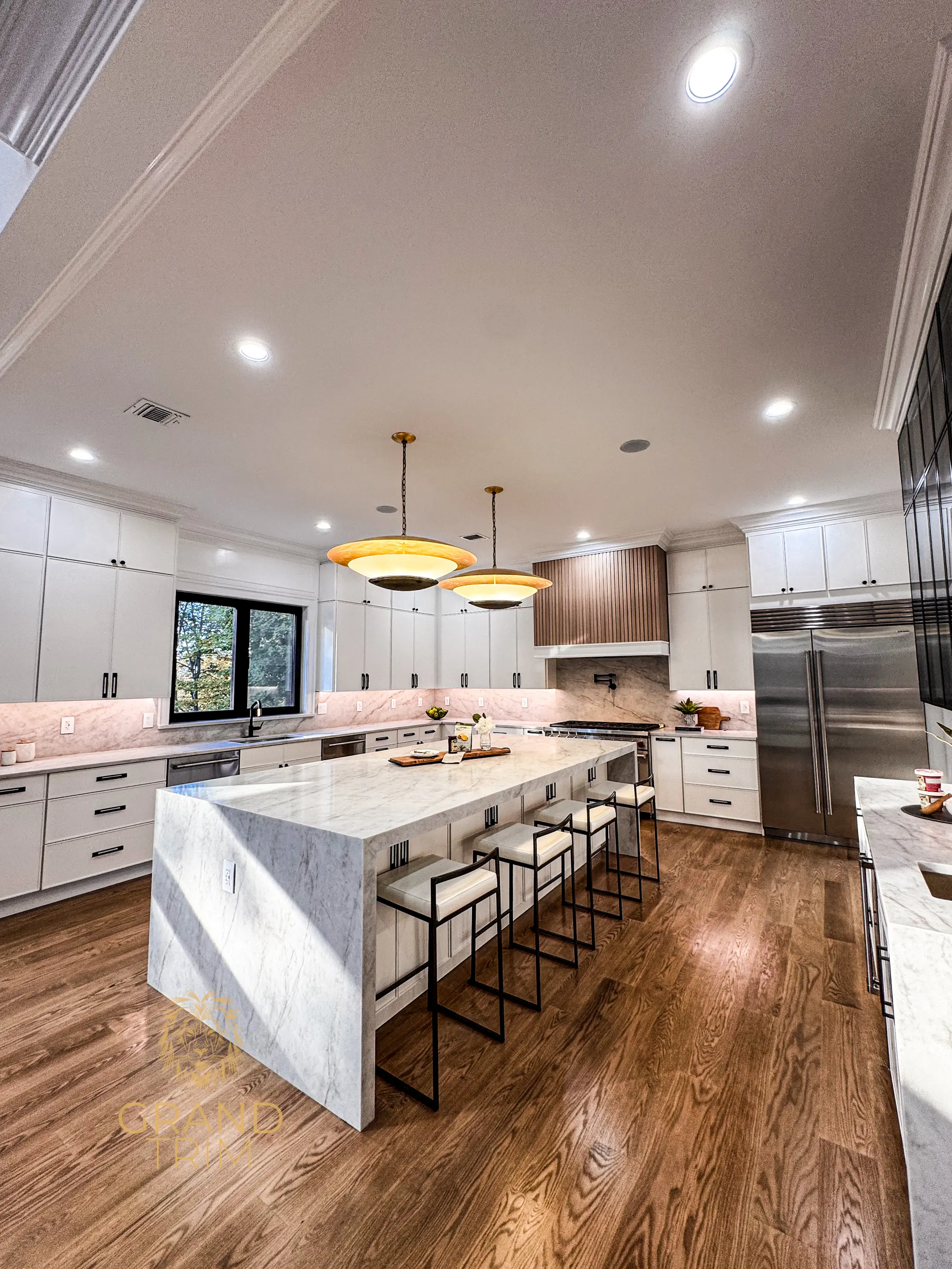 Modern white kitchen cabinetry and crown molding with a large marble island in a New Jersey home