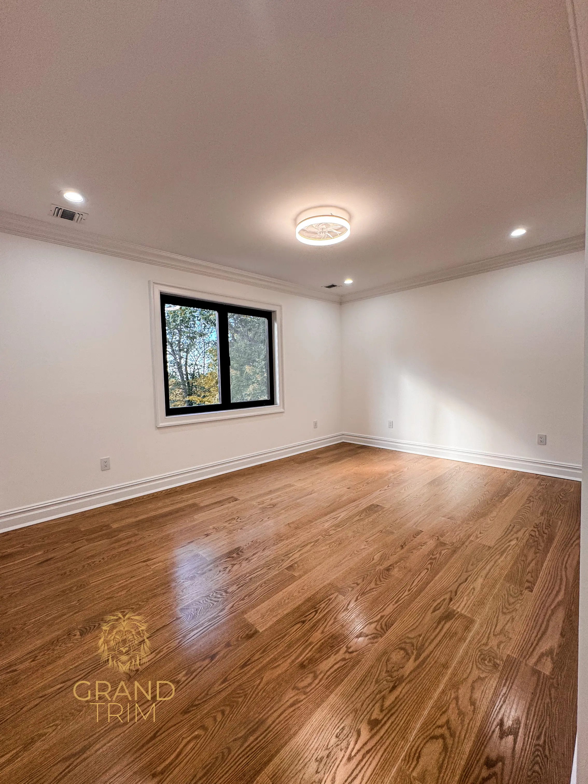 White crown molding, window trim, and baseboard in a newly finished, empty room in New Jersey