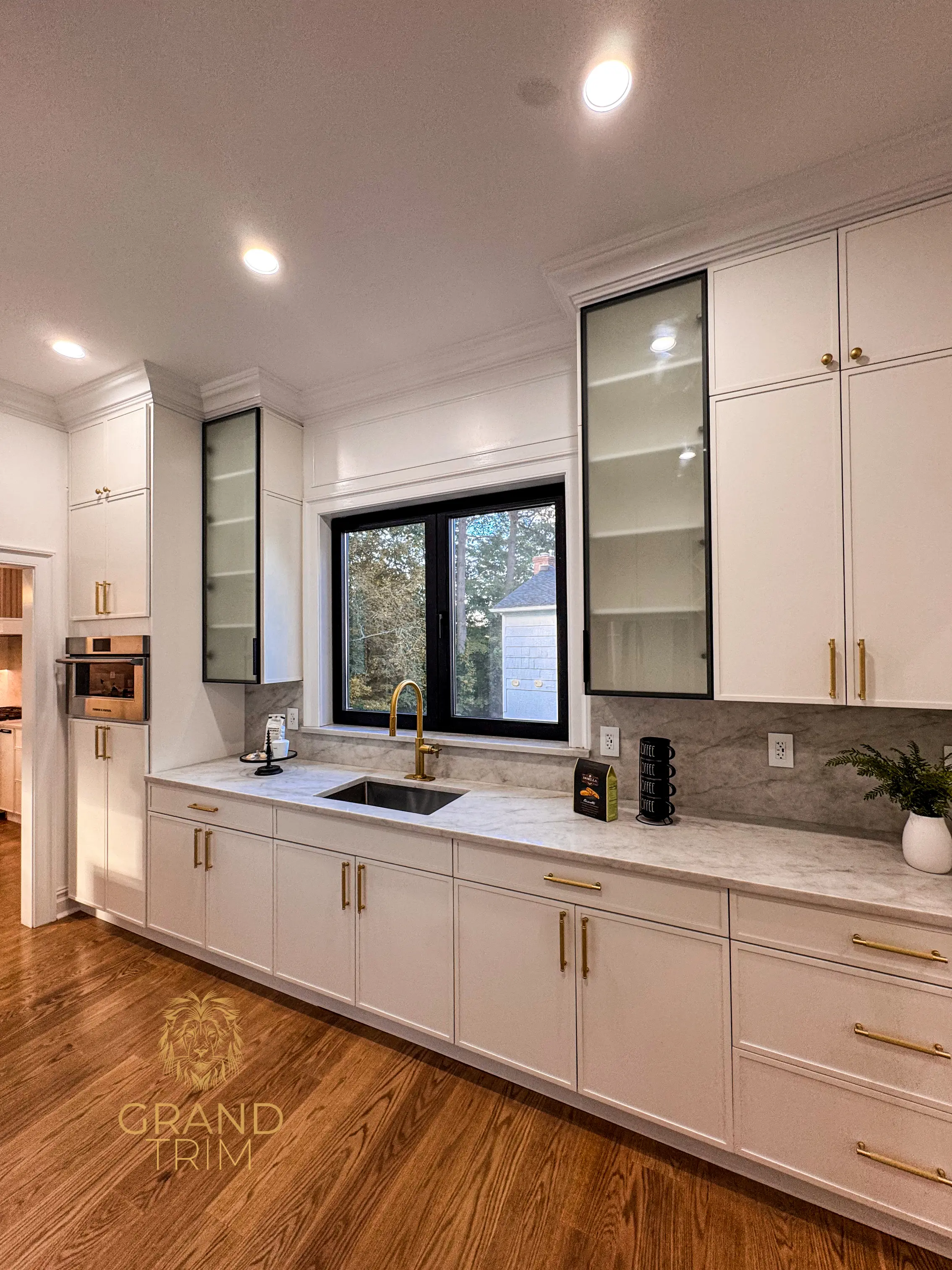 Modern white kitchen cabinets with gold hardware, marble countertops, and crown molding in a New Jersey home