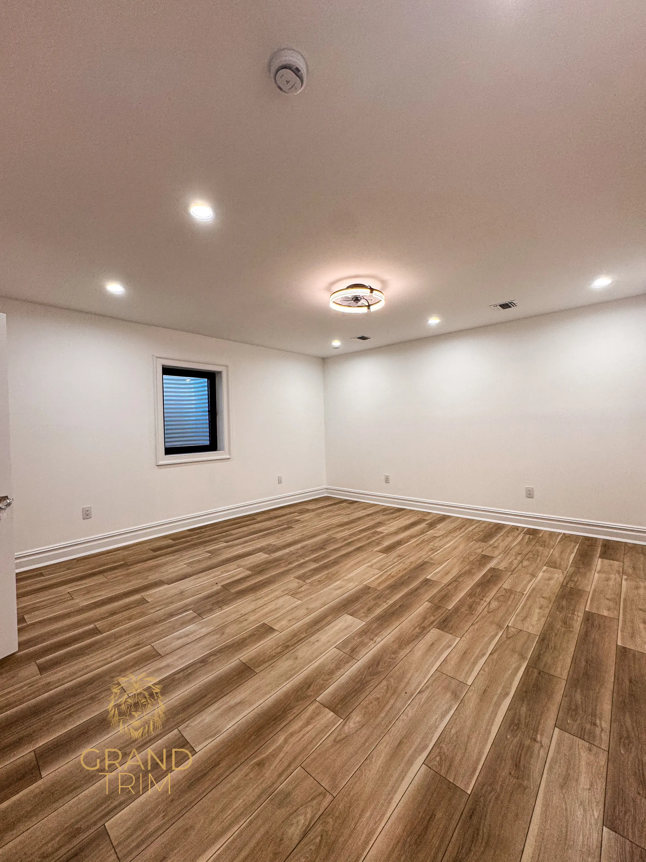 Decorative white baseboard molding installation running along the perimeter of a bright empty room in New Jersey.