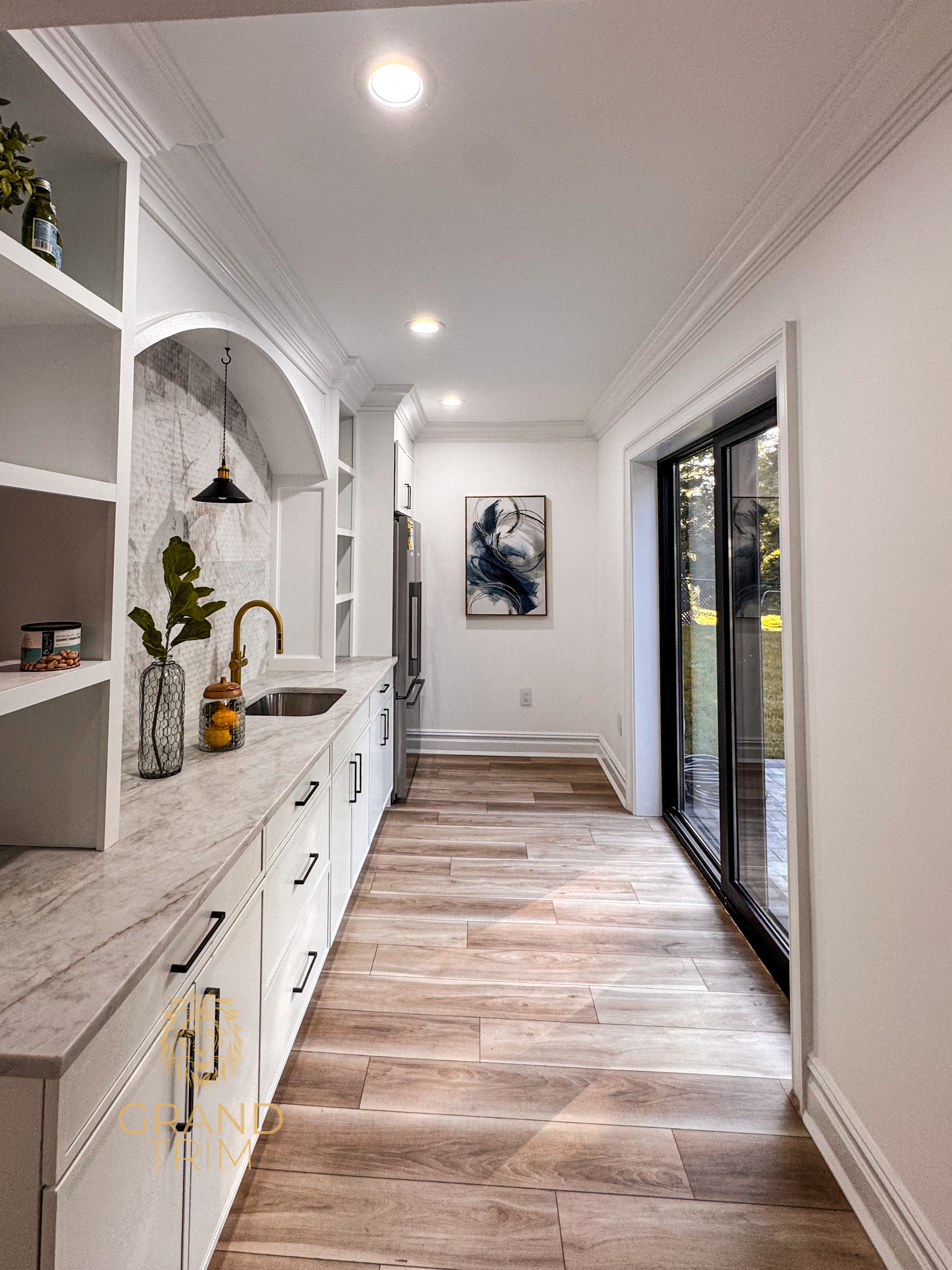 White kitchen cabinetry with marble countertop, sink, and prominent crown molding in a New Jersey butler's pantry