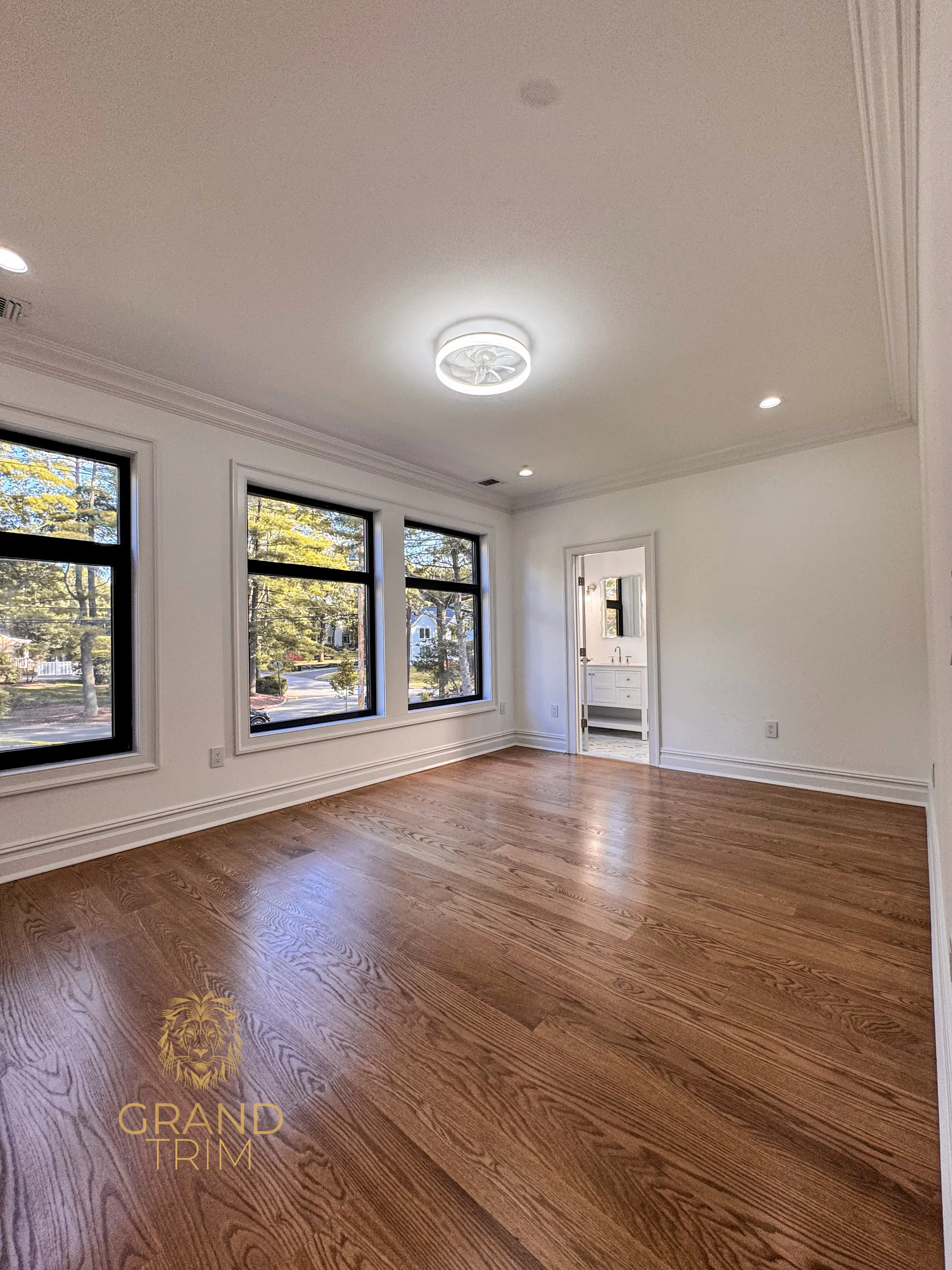 White crown molding, window casings, and tall baseboard in a newly finished empty room in NJ
