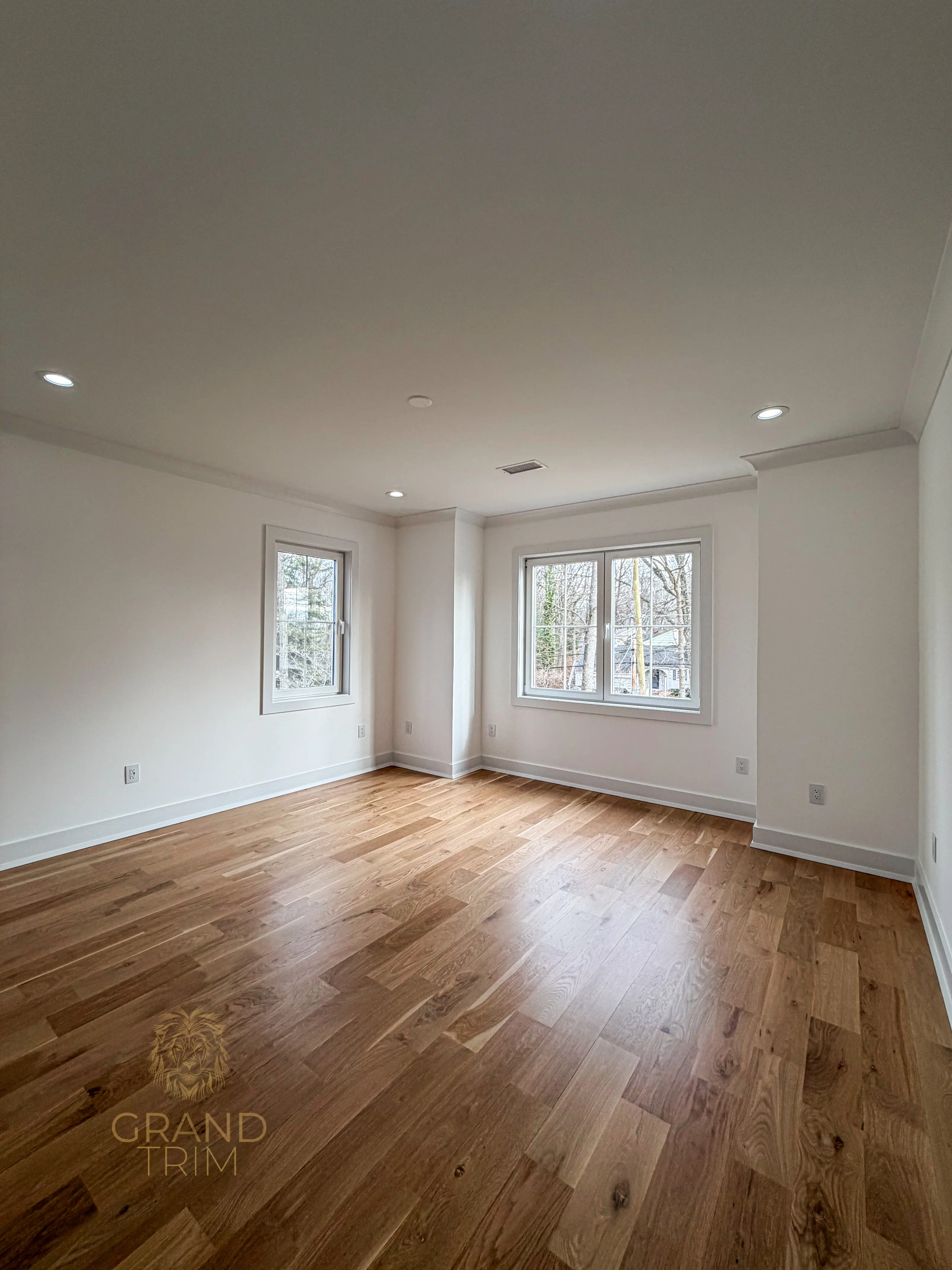 White crown molding and window casing in a newly finished, empty room with hardwood floors in New Jersey