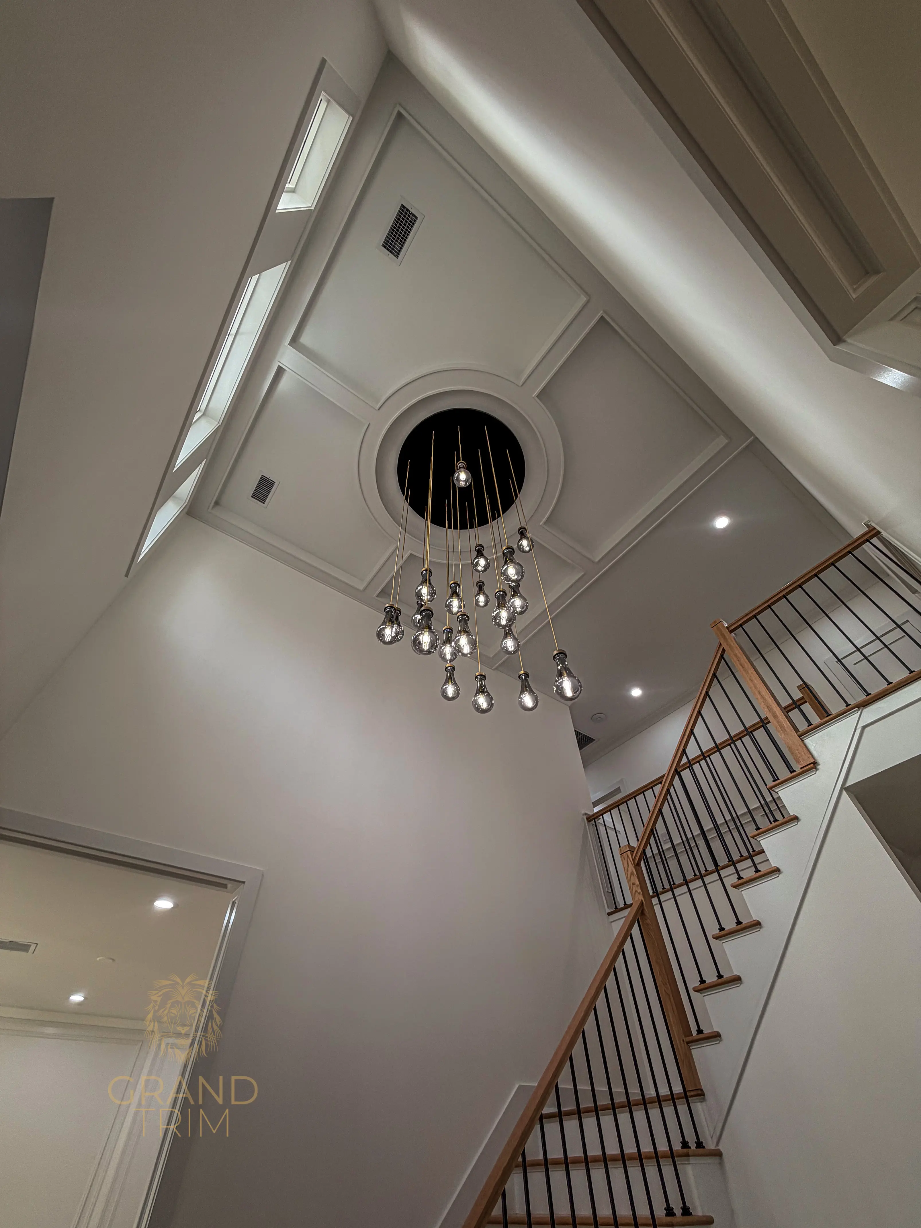 White coffered ceiling with recessed panels and a chandelier in a New Jersey home entryway with a grand staircase