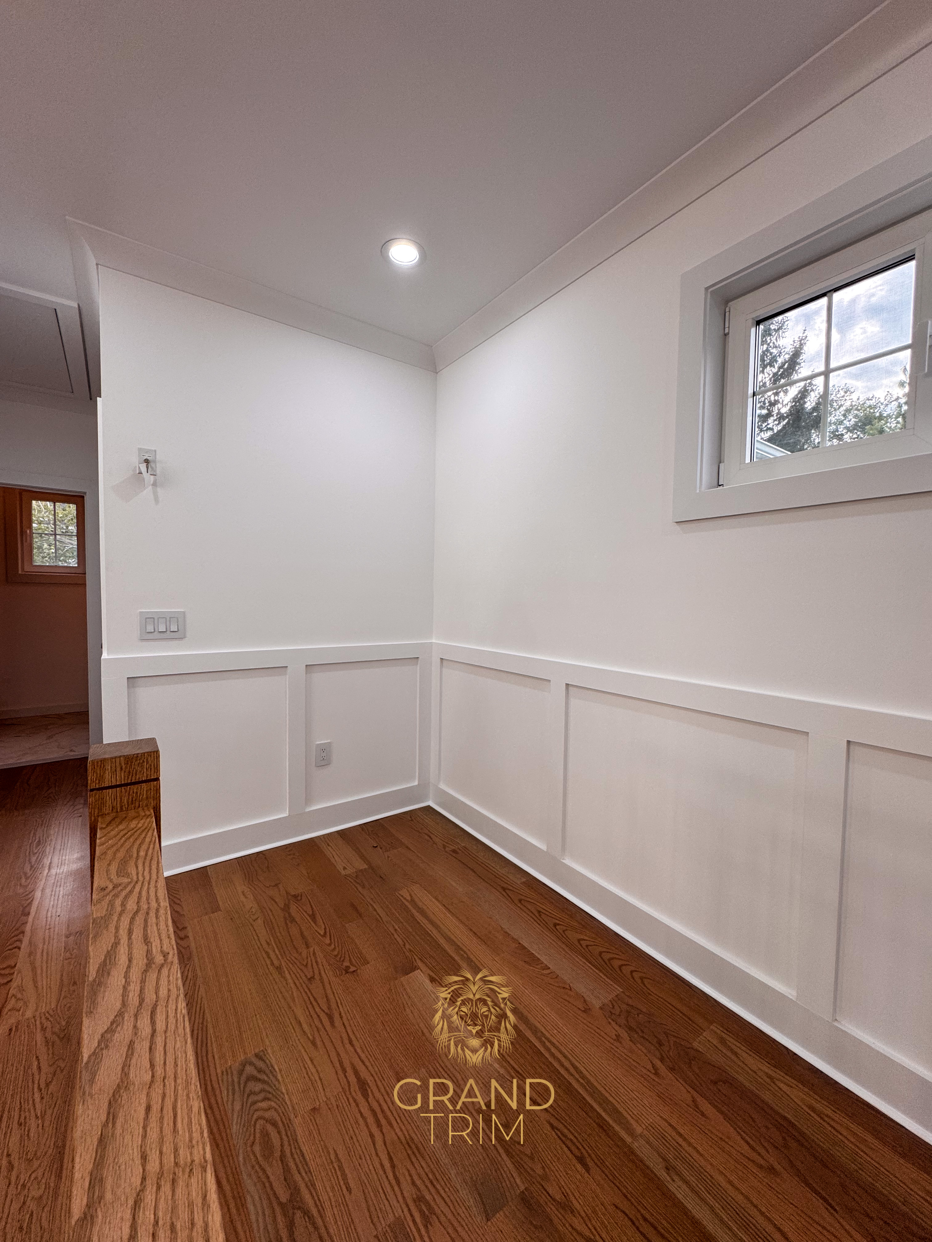 White board-and-batten wall paneling with crown molding and window trim in a New Jersey hallway