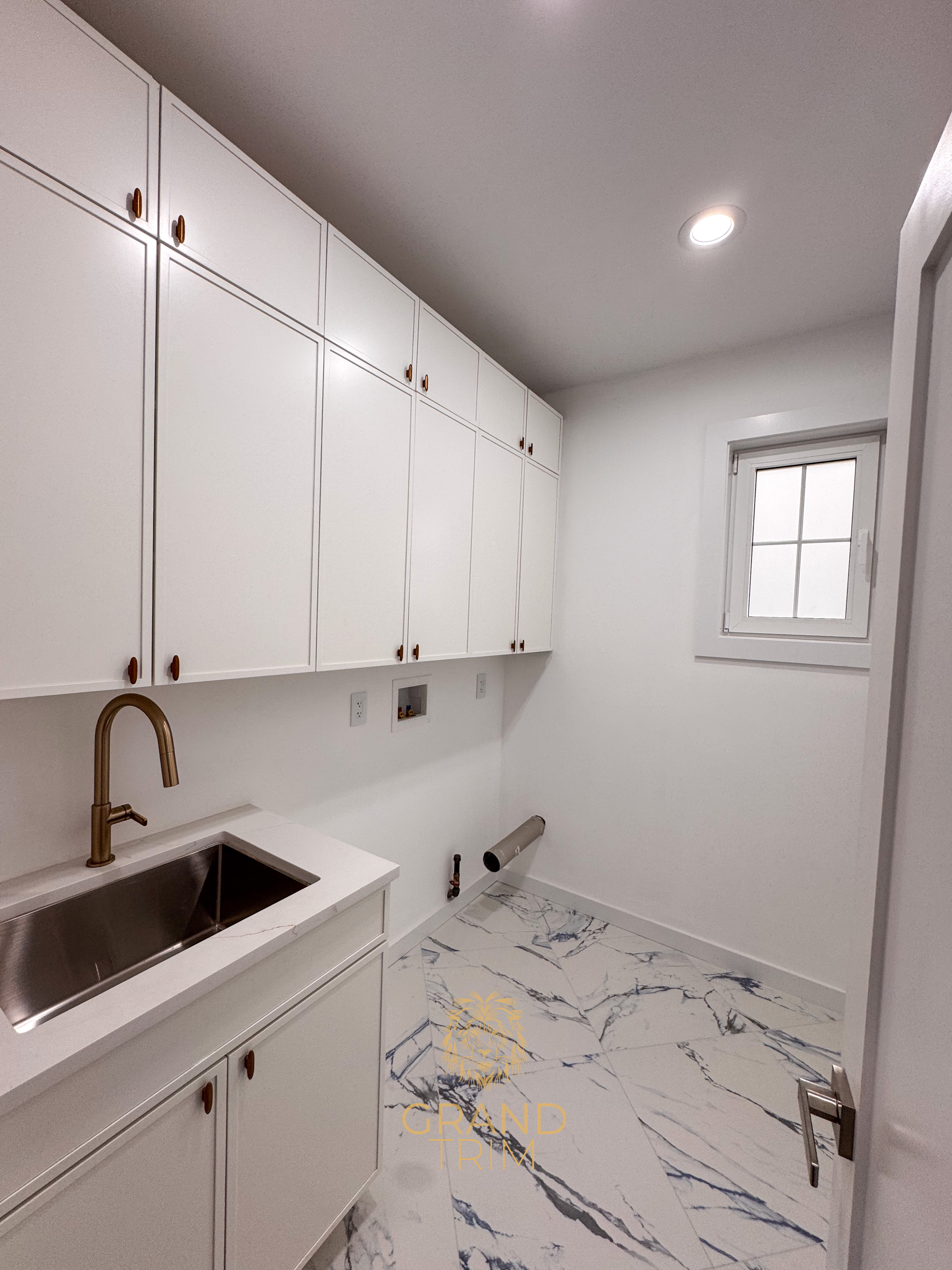 White custom cabinetry, sink, and quartz countertop in a modern New Jersey laundry room