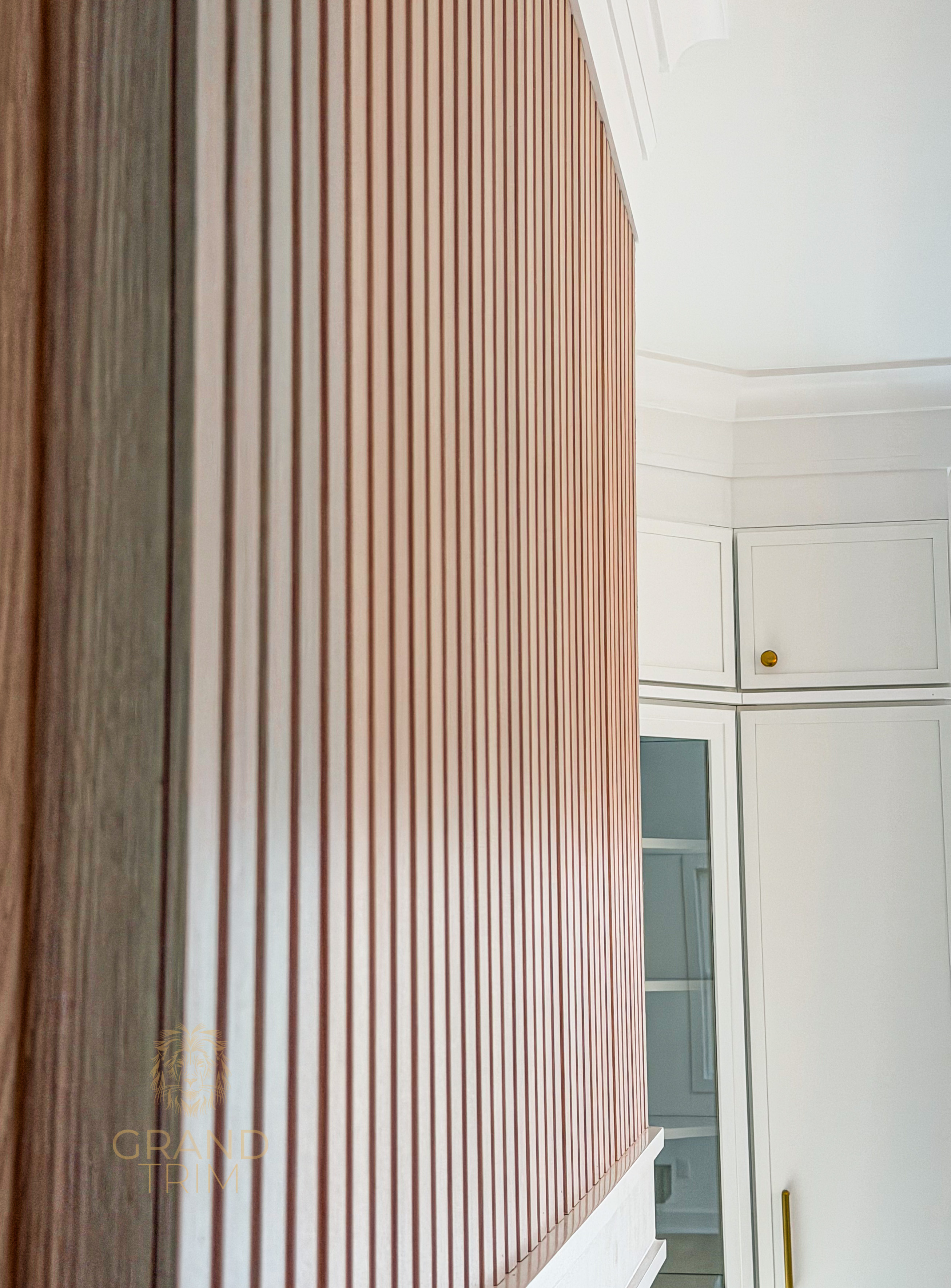 Modern wooden slat wall paneling next to white custom built-in cabinetry and crown molding in a New Jersey home.
