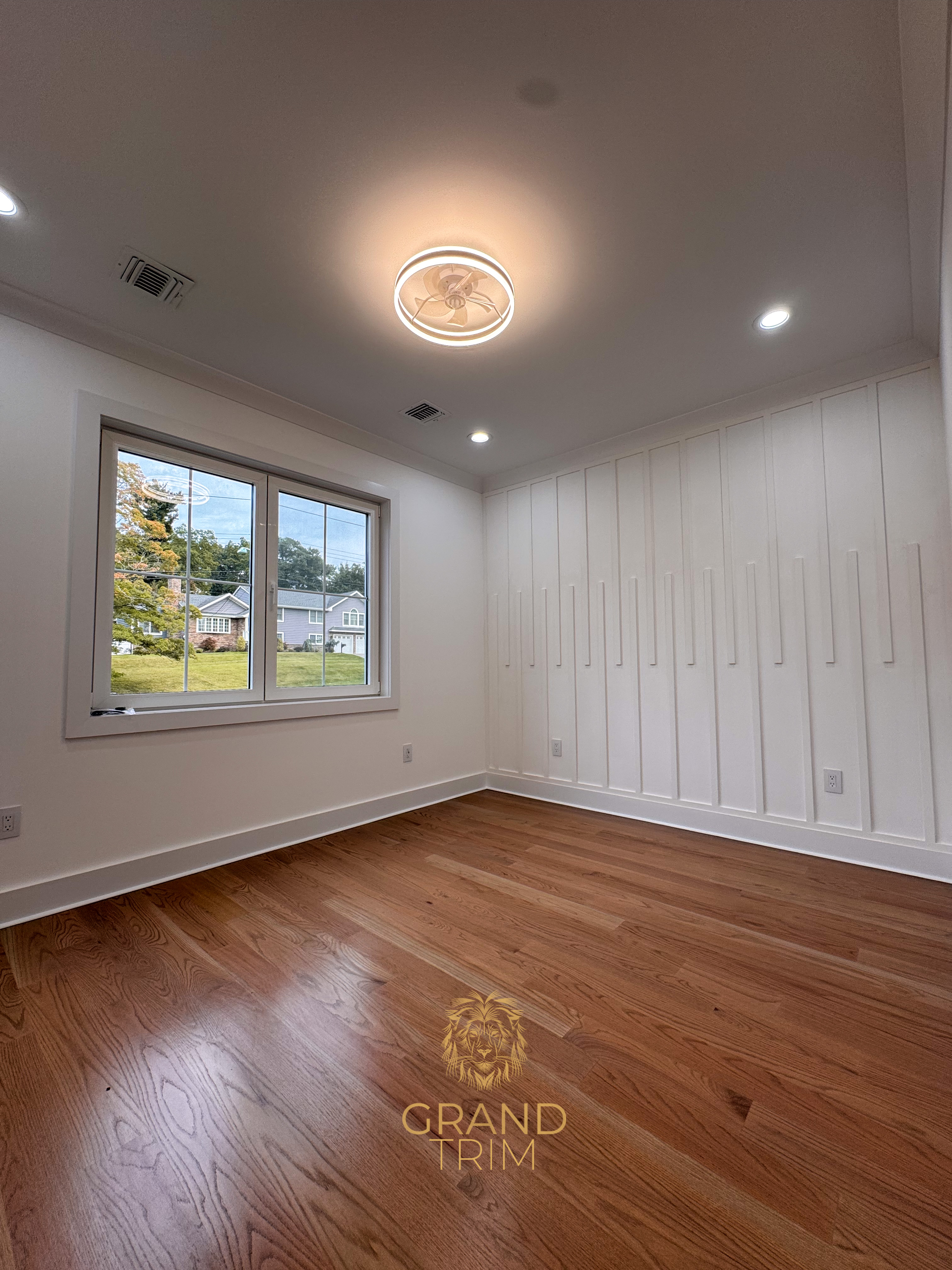 White modern vertical wall paneling and window trim in an empty room with hardwood floors in New Jersey