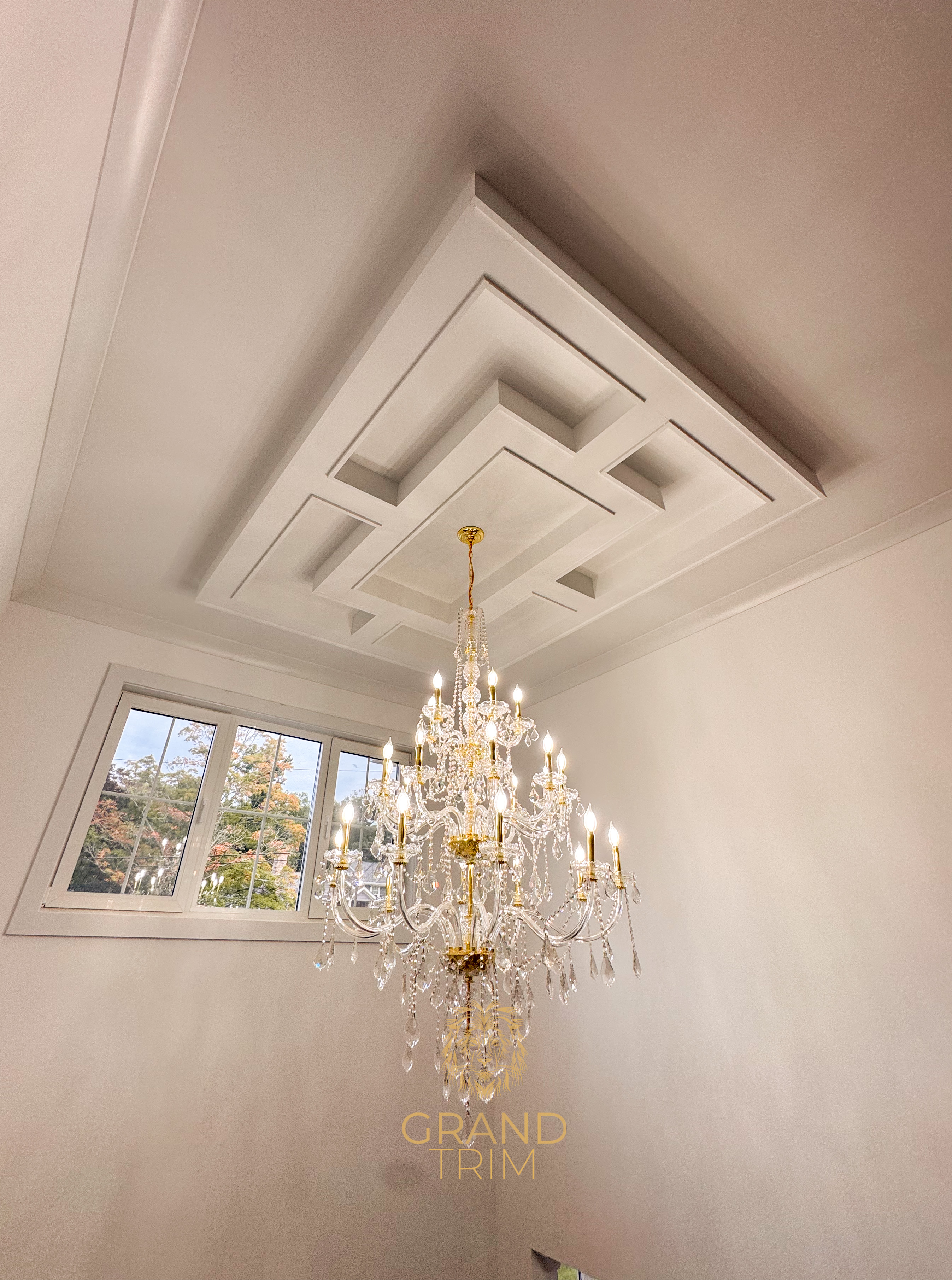 White coffered ceiling with a complex geometric design and a crystal chandelier in a New Jersey home