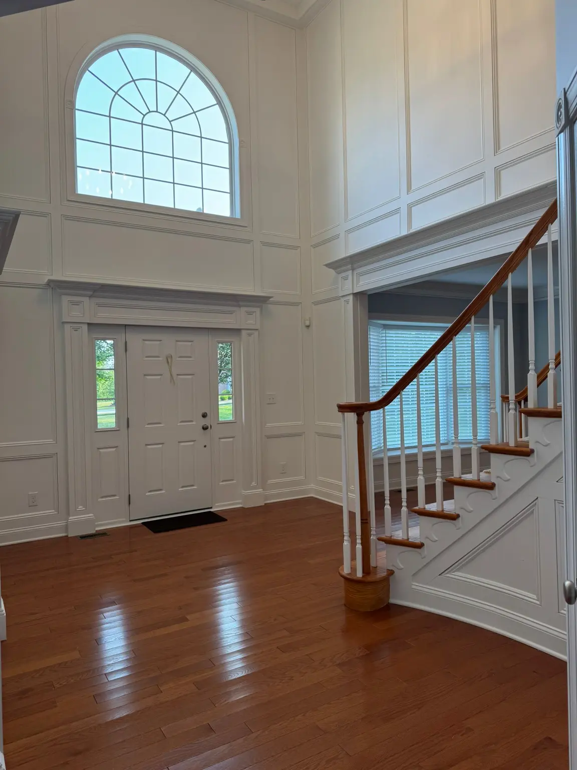 Floor-to-ceiling white decorative wall paneling and crown molding in a two-story New Jersey entryway.