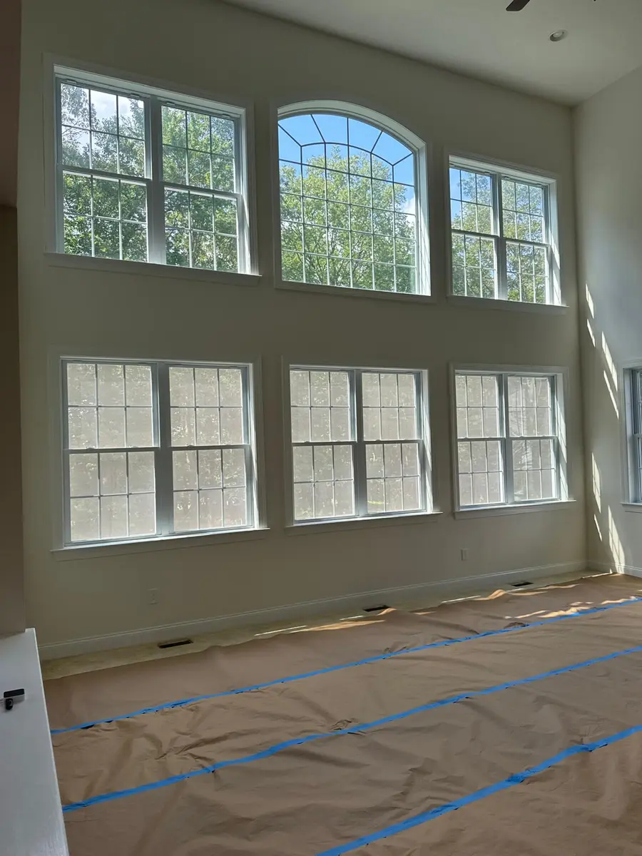 Tall white window casings in a spacious, sunlit living room with high ceilings in New Jersey