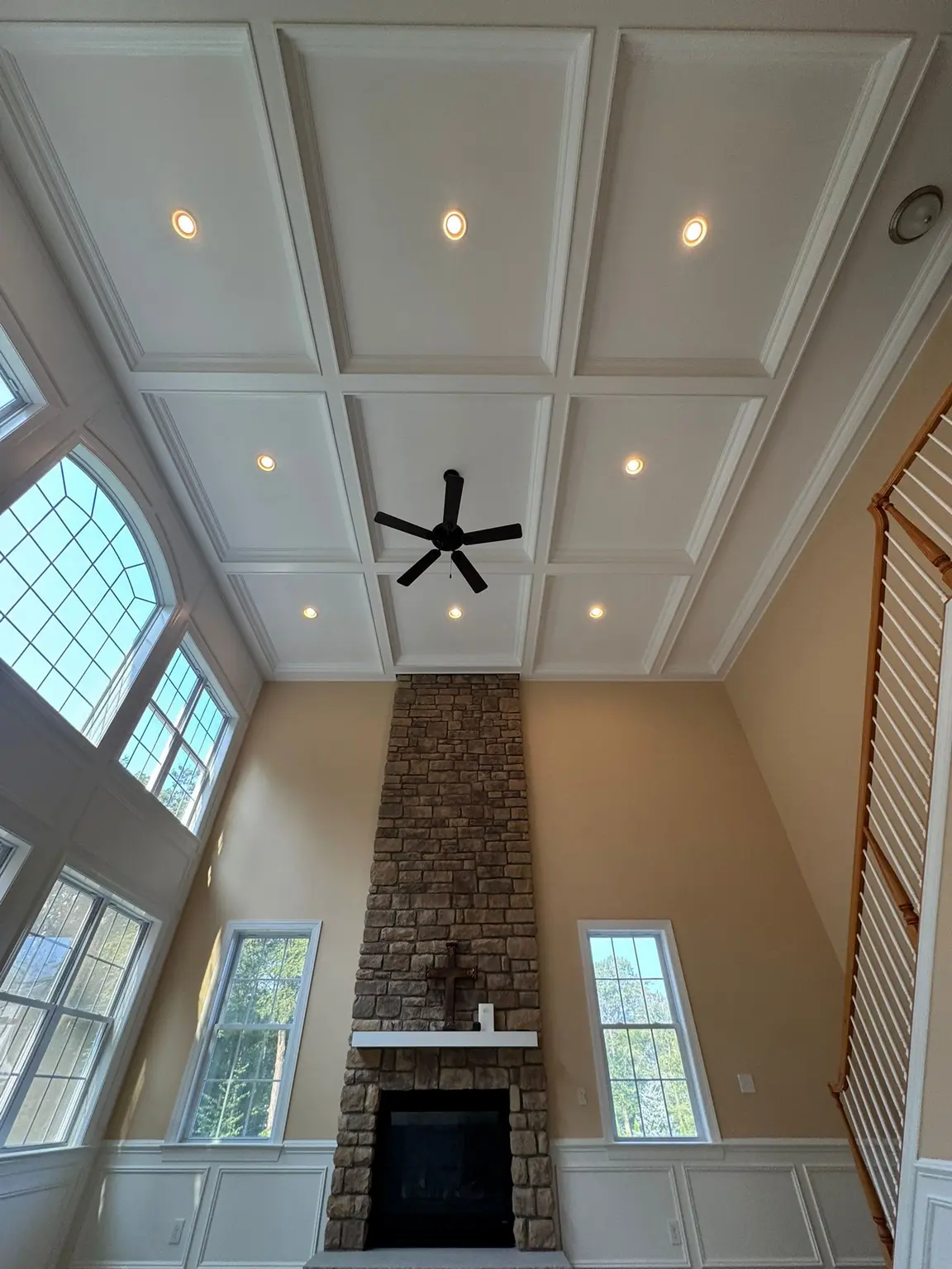 White coffered ceiling over a tall stone fireplace and wainscoting in a New Jersey living room