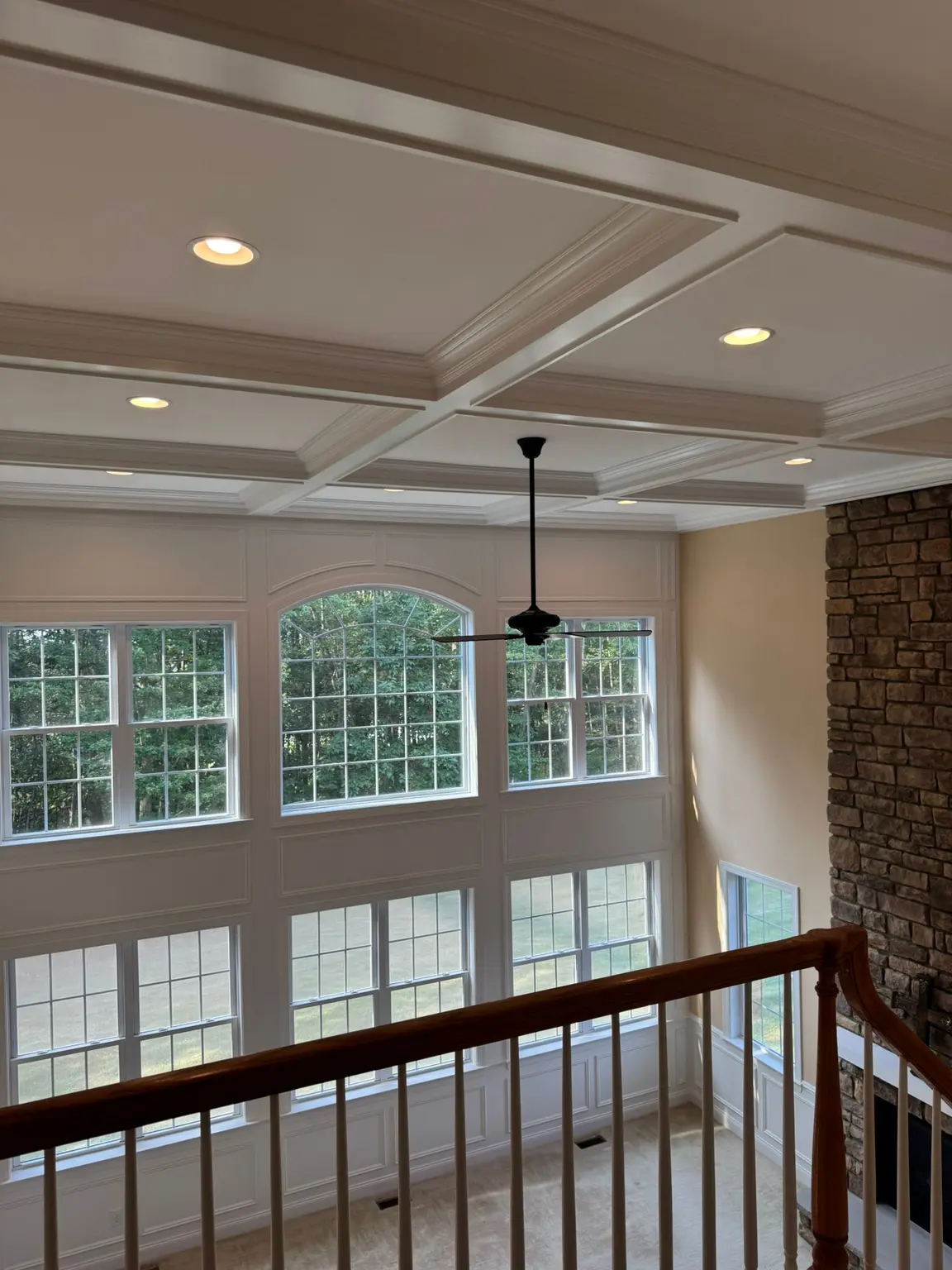White coffered ceiling with recessed panels and elegant wall paneling below multiple large windows in a spacious New Jersey home