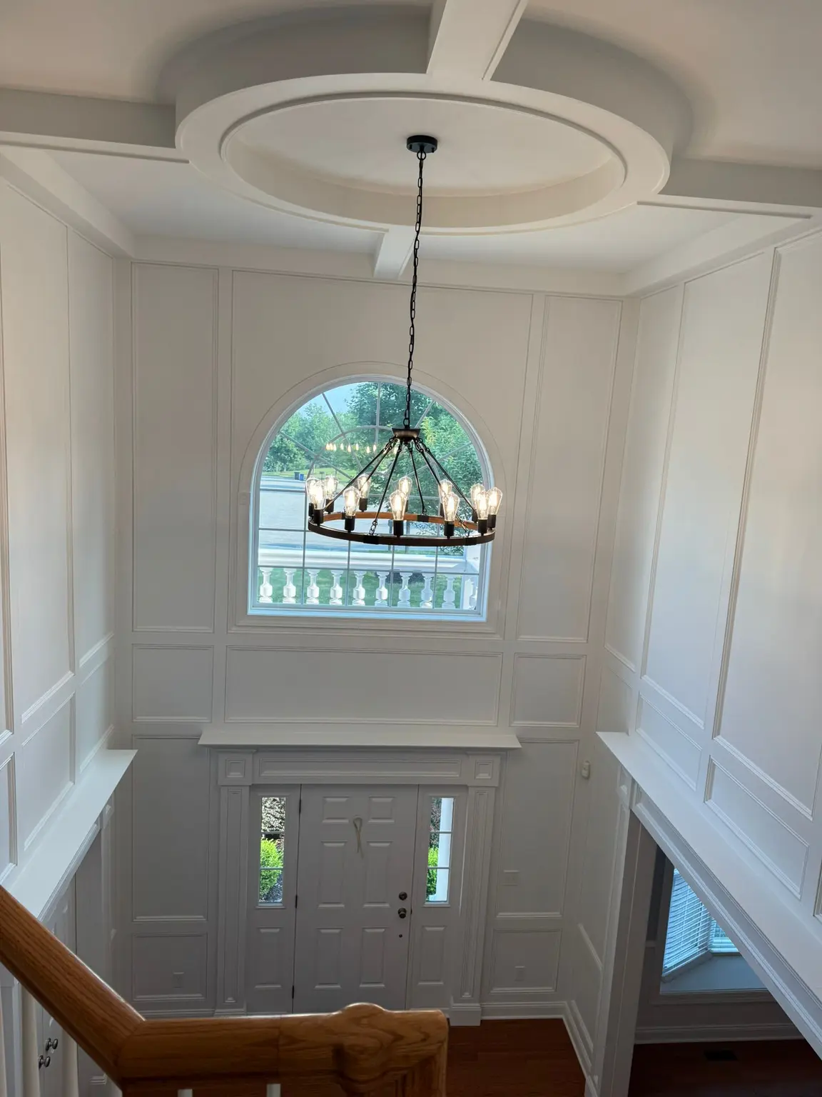 White full-height wall paneling in a grand New Jersey entryway with a decorative ceiling.