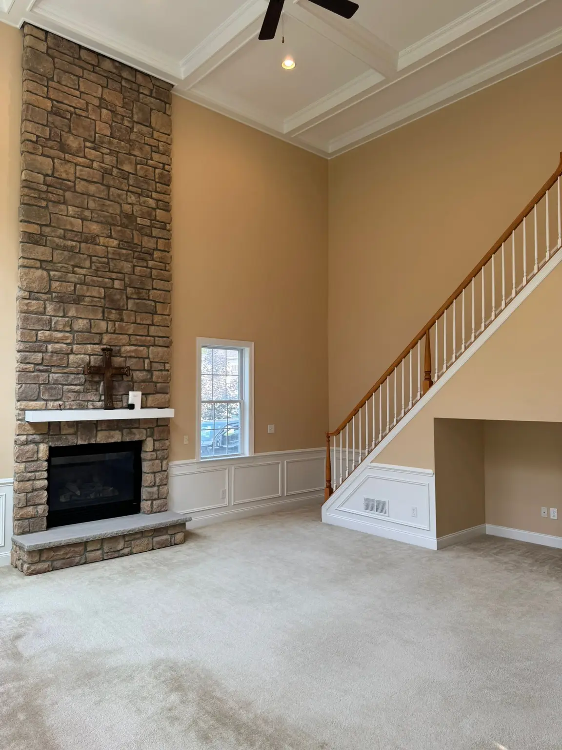Spacious living room with stone fireplace, white wainscoting, and a detailed coffered ceiling in New Jersey