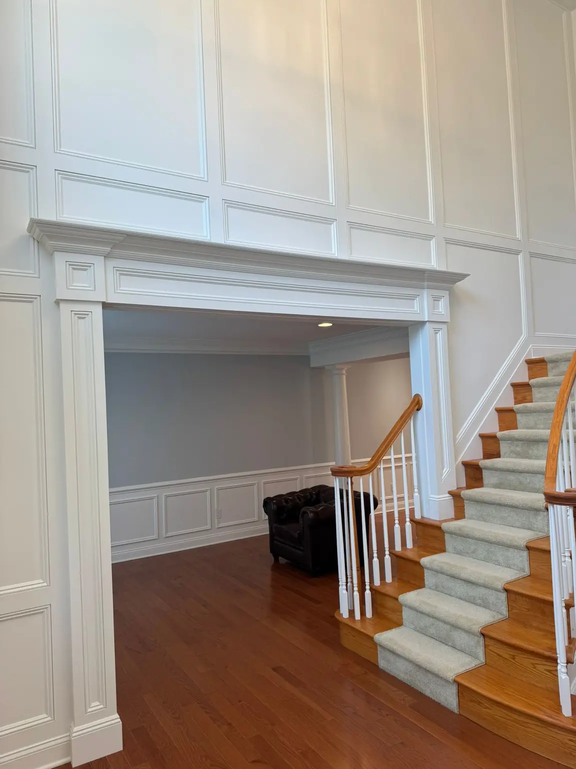 White raised panel wall paneling with an elaborate trim archway and staircase in a New Jersey home