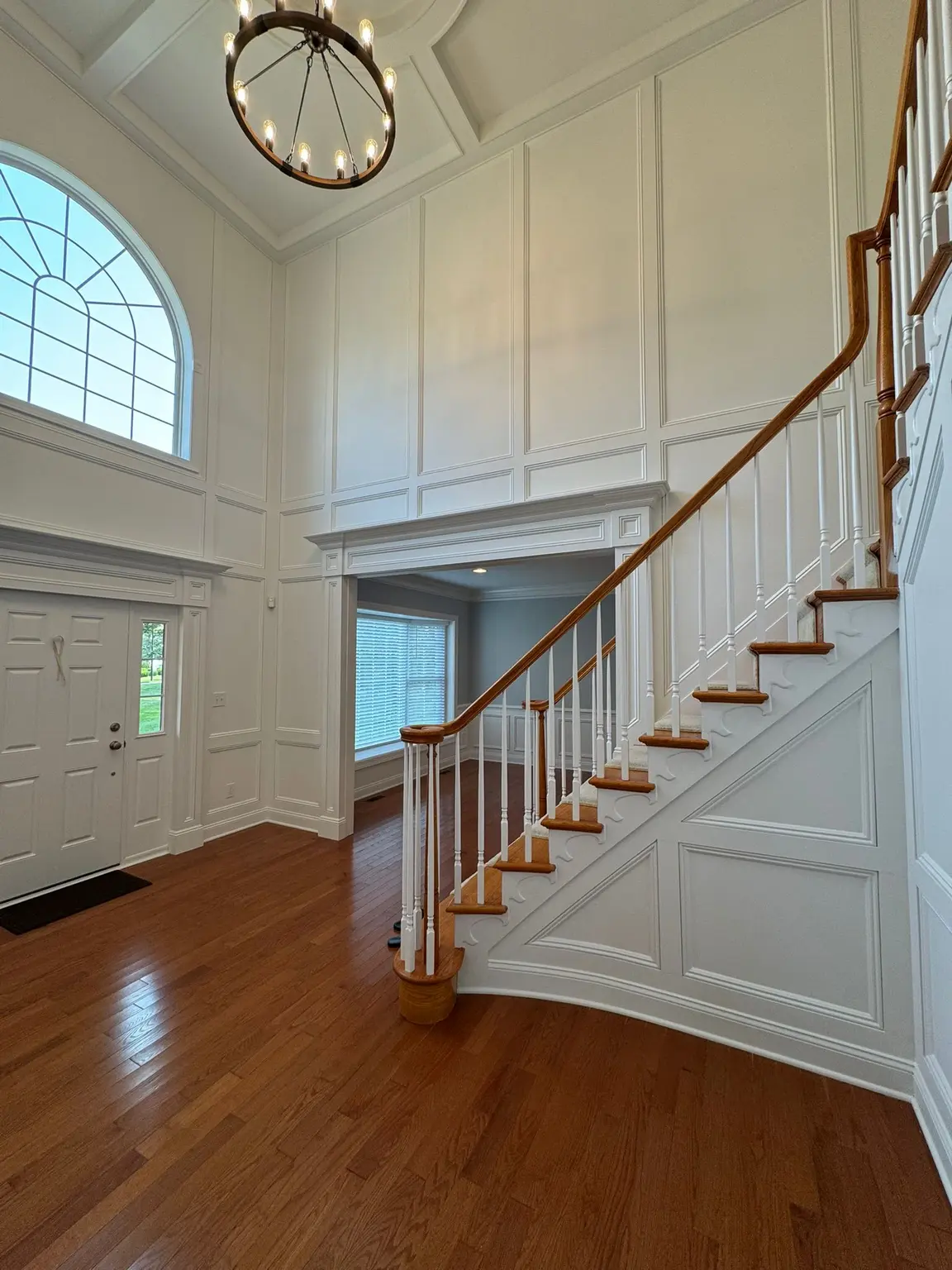 White decorative wall paneling and a detailed tray ceiling in a grand entryway foyer in New Jersey