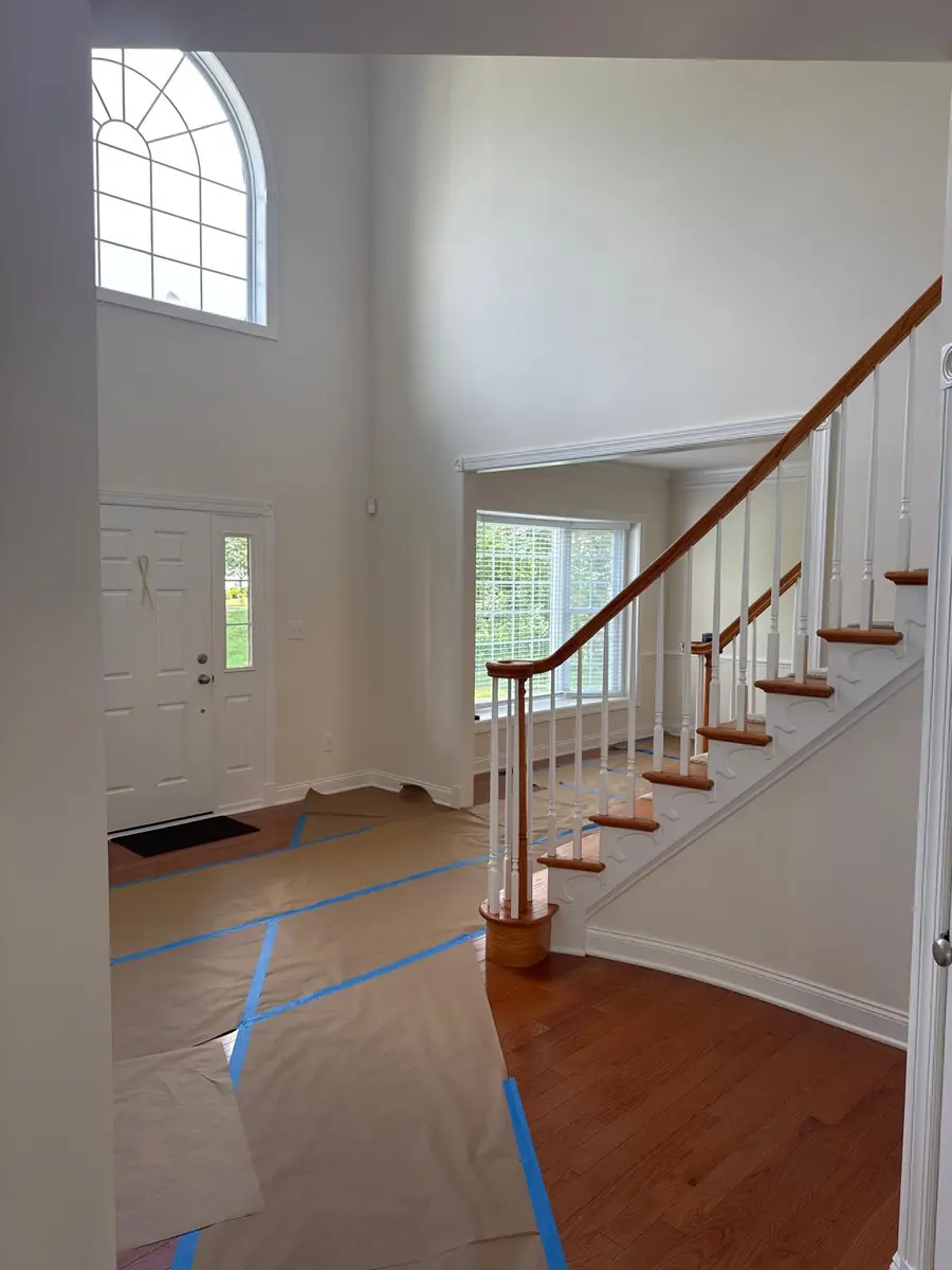 White trim around arched window, front door, and cased opening in a high-ceiling New Jersey entryway