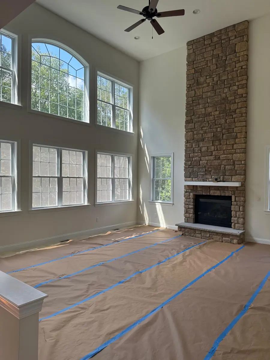 Tall stone fireplace with white mantel and hearth in a spacious New Jersey living room
