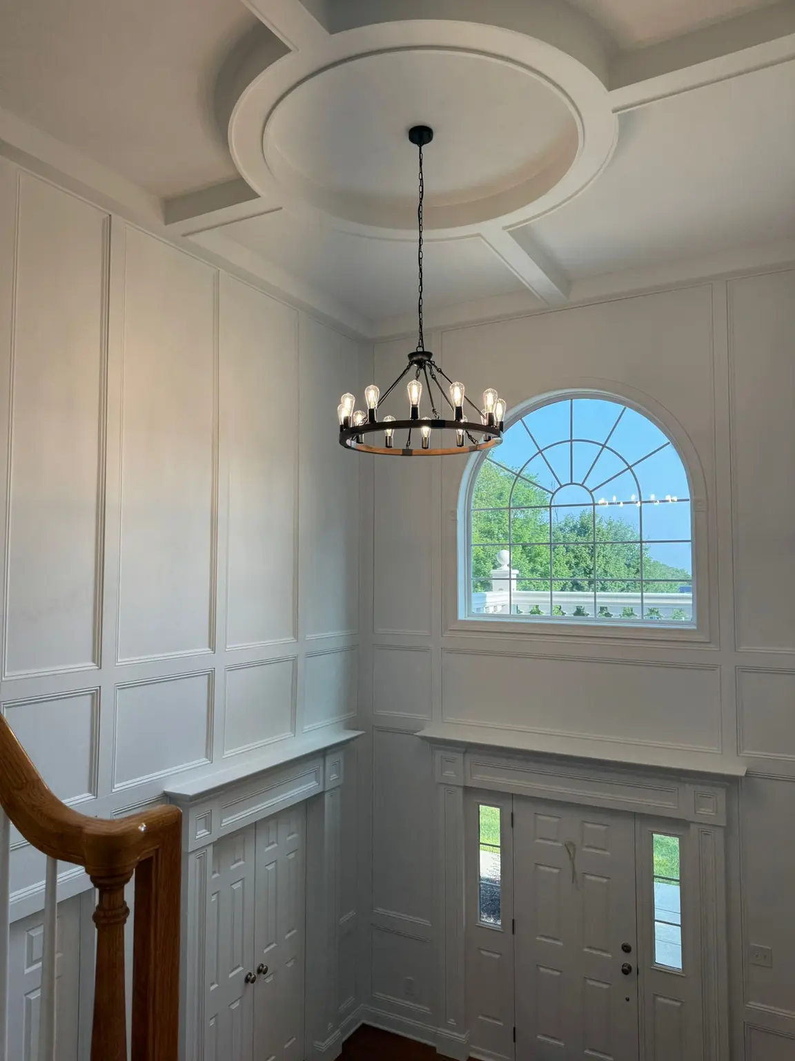 Elegant white wall paneling and a coffered ceiling with a circular medallion in a New Jersey foyer