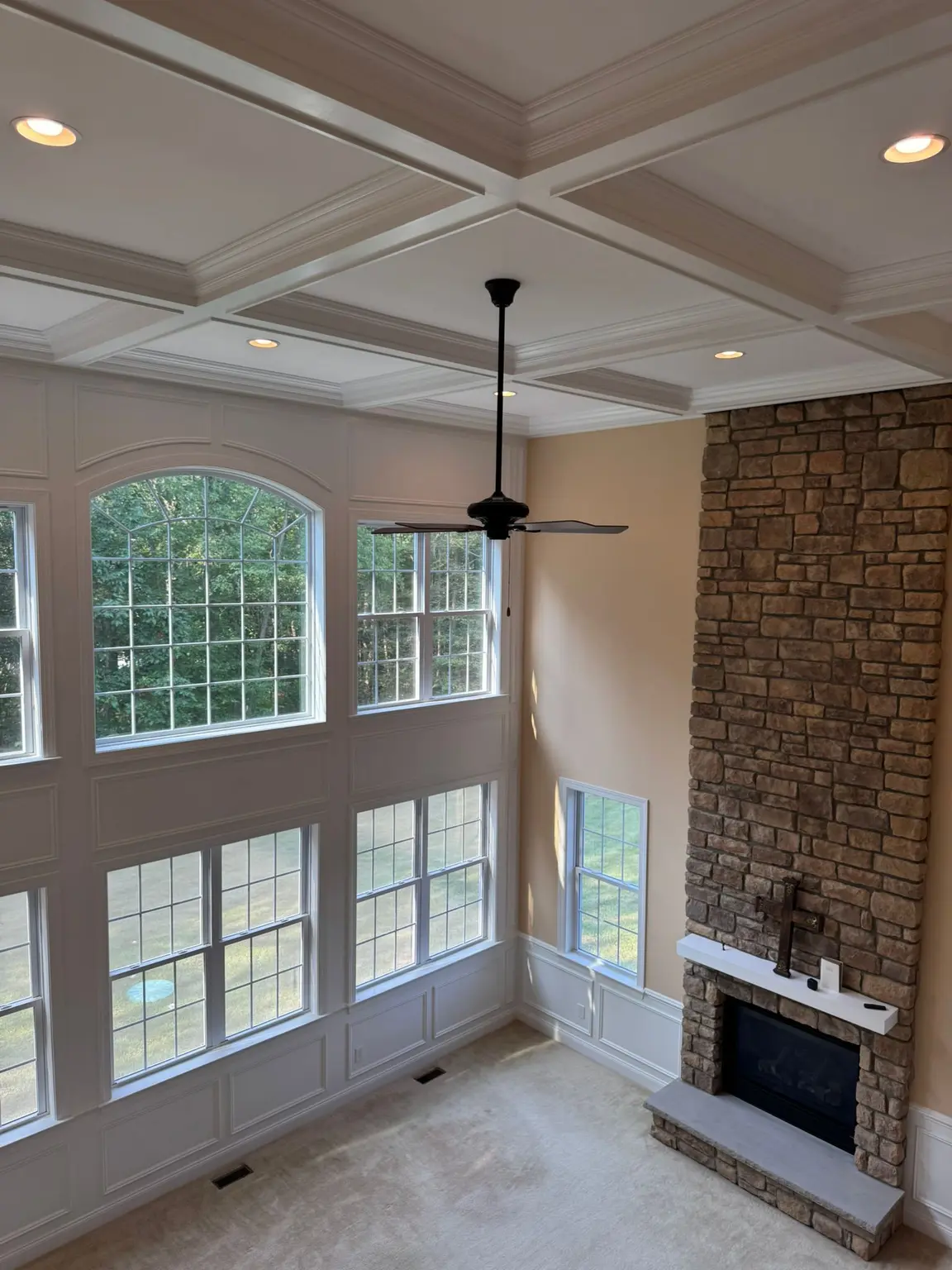 Grand living room with white coffered ceiling, detailed wall paneling, and stone fireplace in New Jersey