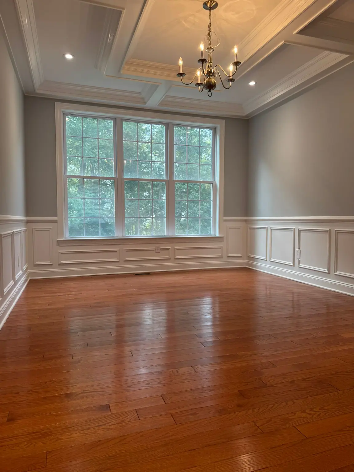 White coffered ceiling and wainscoting with elaborate window trim in an empty NJ room