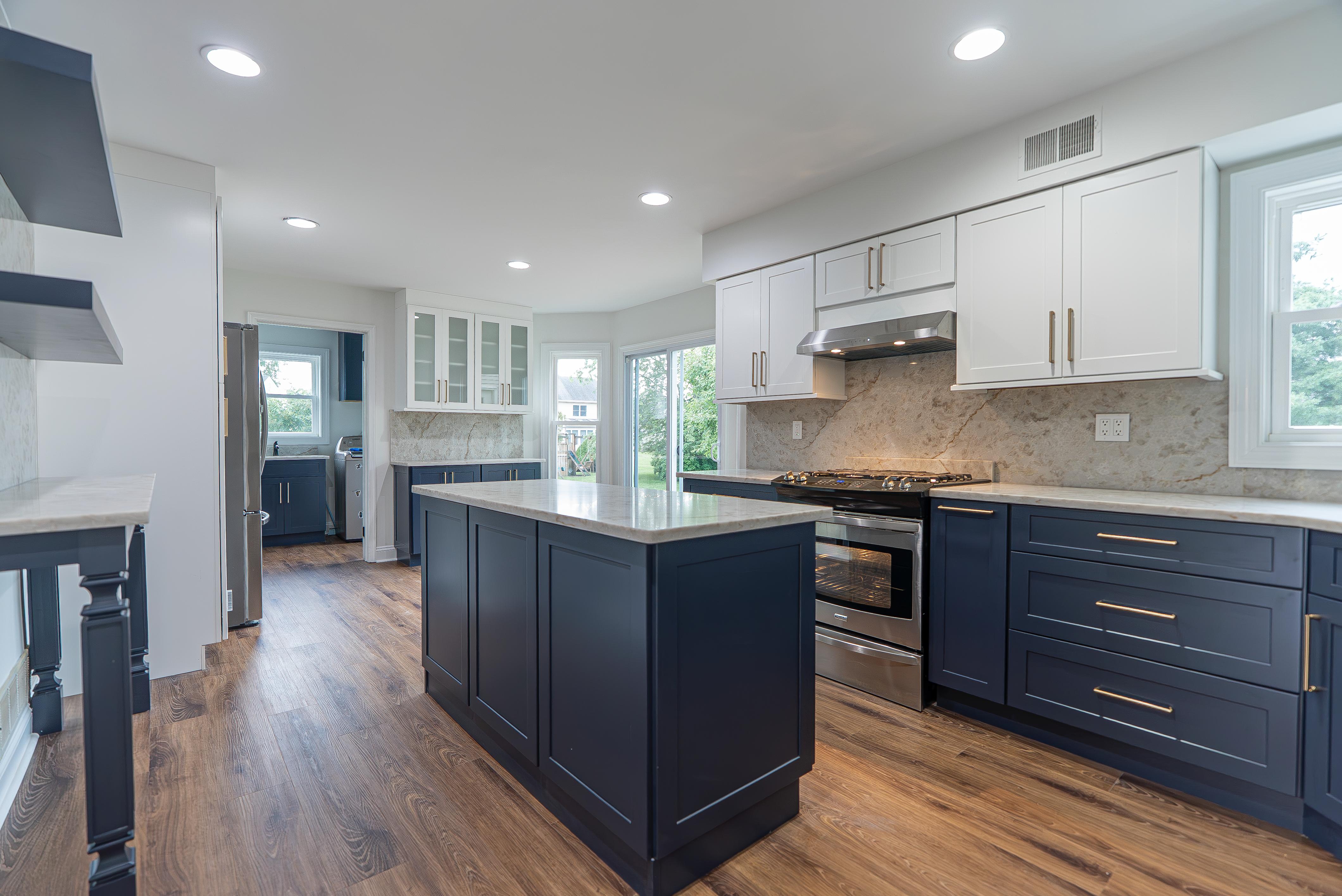 Sleek kitchen in NJ featuring custom white upper and navy blue lower cabinetry, an island, and light marble countertops