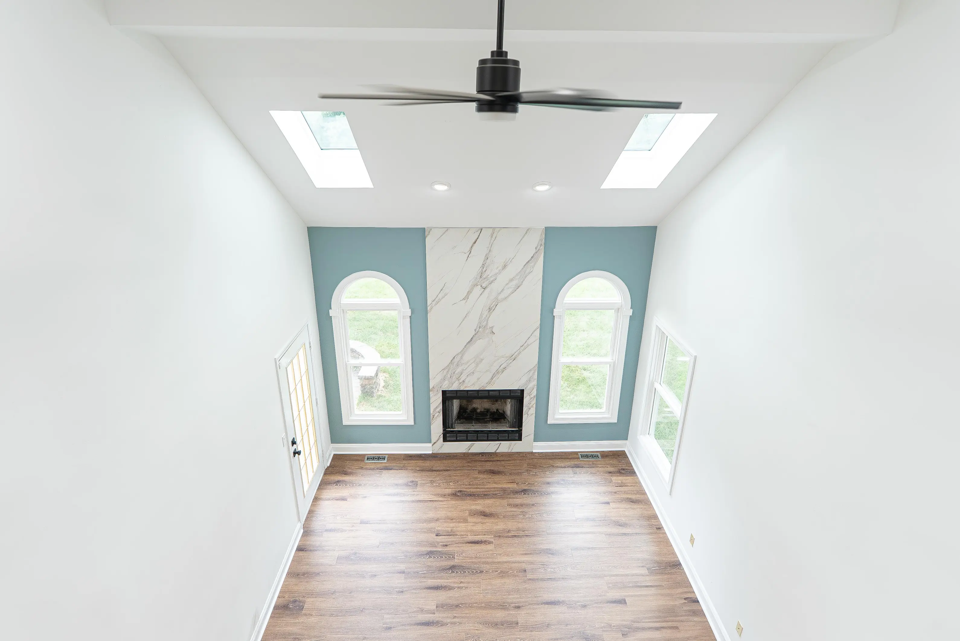 Modern fireplace with white marble surround and dark firebox in a vaulted New Jersey living room