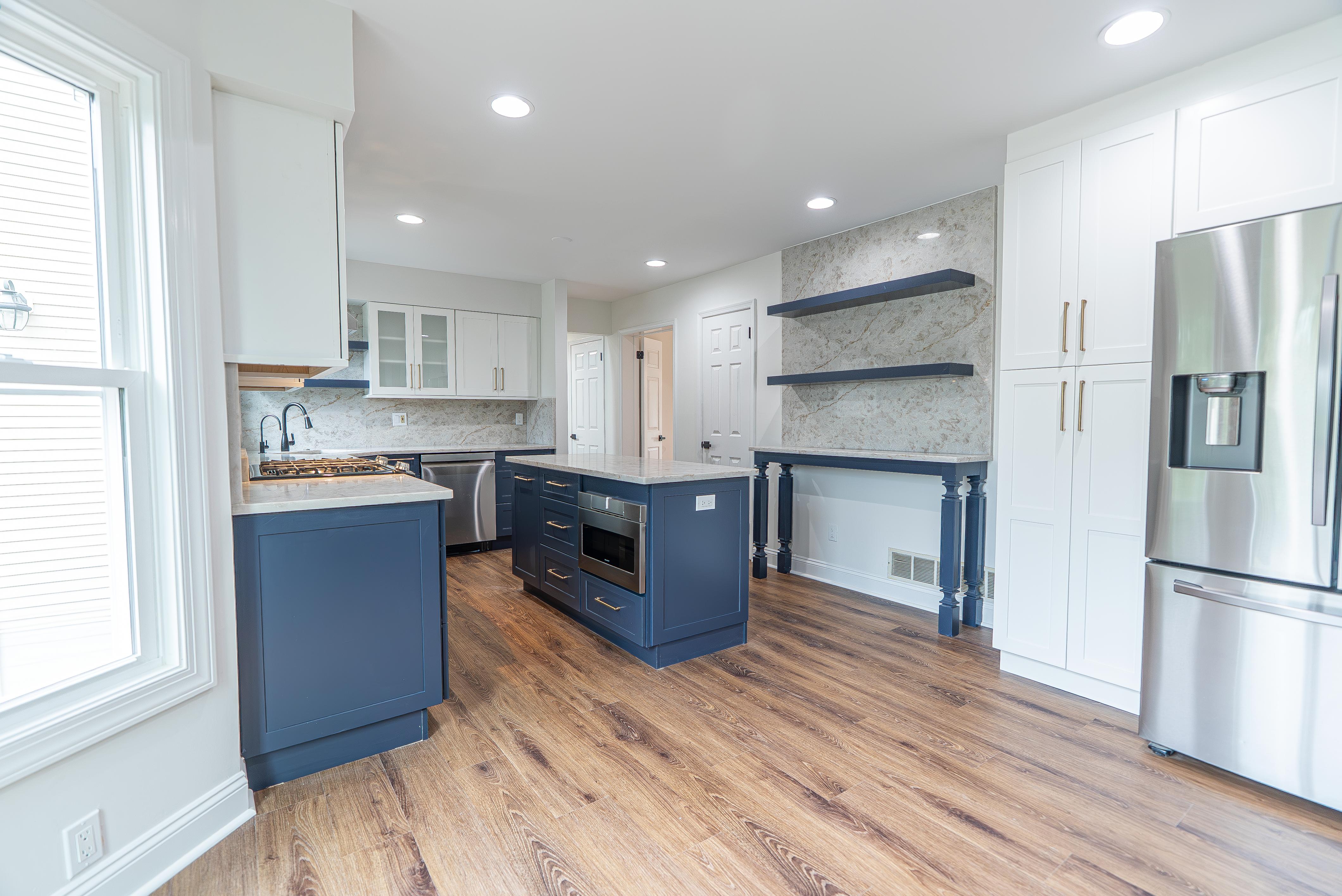 Modern kitchen with white and navy blue custom cabinets, a large island, and stainless steel appliances in New Jersey