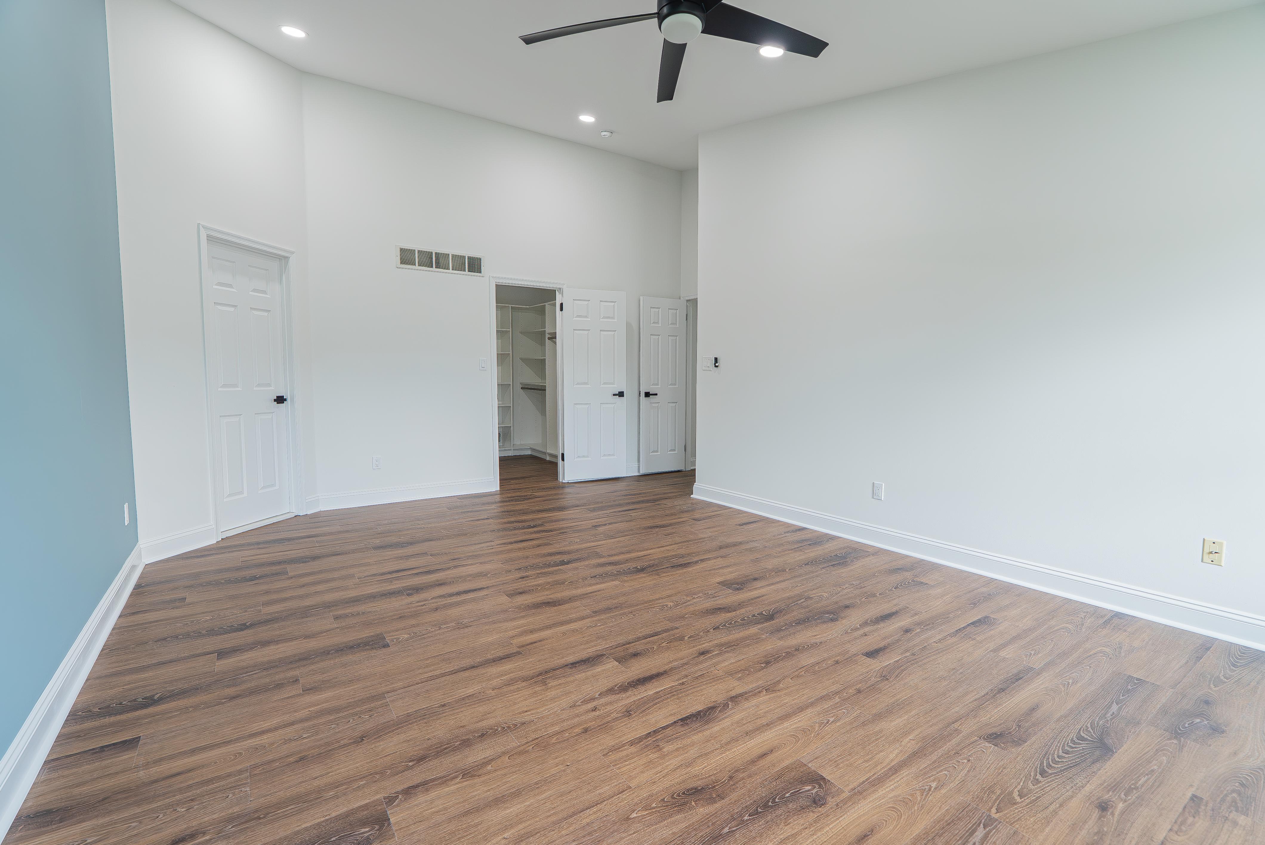 Empty bedroom with open custom walk-in closet featuring white built-in shelving and hanging rods in New Jersey