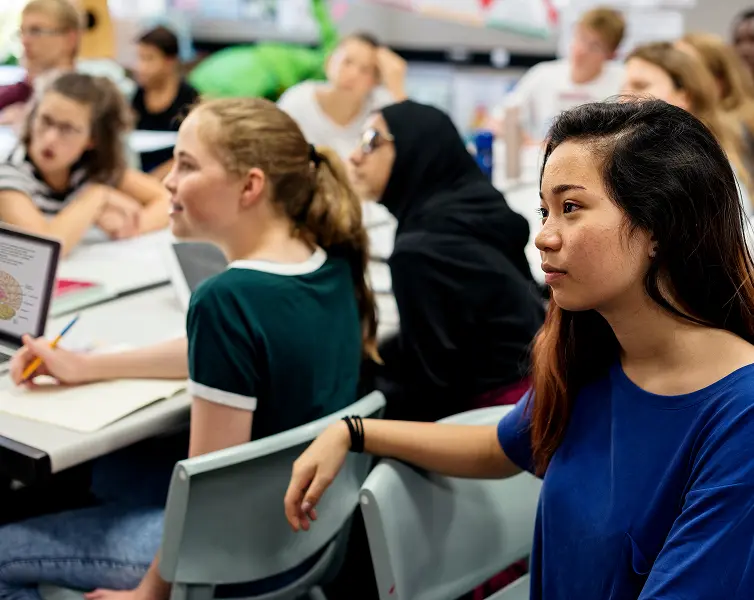 Diverse students attentively listening during a high school classroom lesson