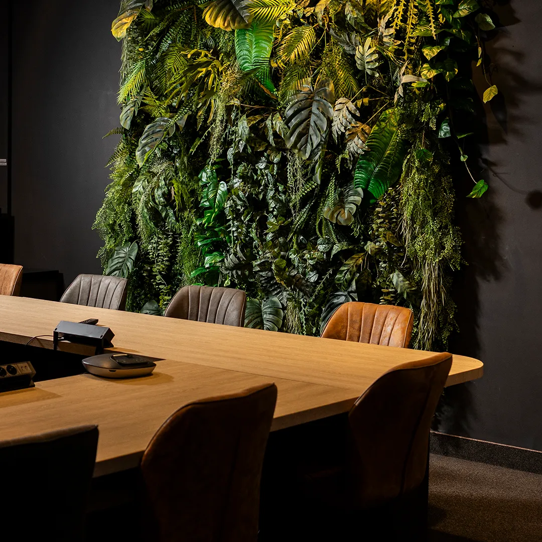 Maatwerk groene plantenwand met tropische bladeren in een stijlvolle vergaderruimte