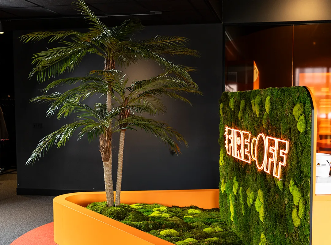 Maatwerk palmbomen naast een moswand met neonlogo van Fire Off in een modern kantoorinterieur