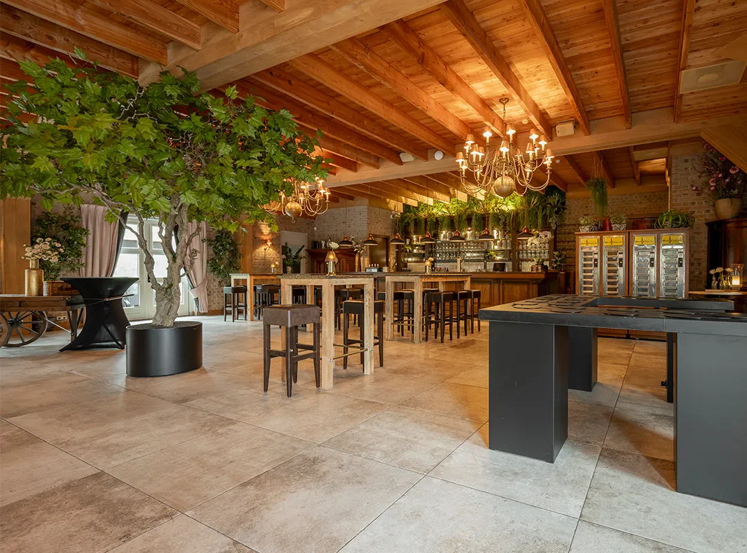 Grote maatwerk kunstboom in een open huurbare evenementenruimte met houten plafond en sfeervolle bar