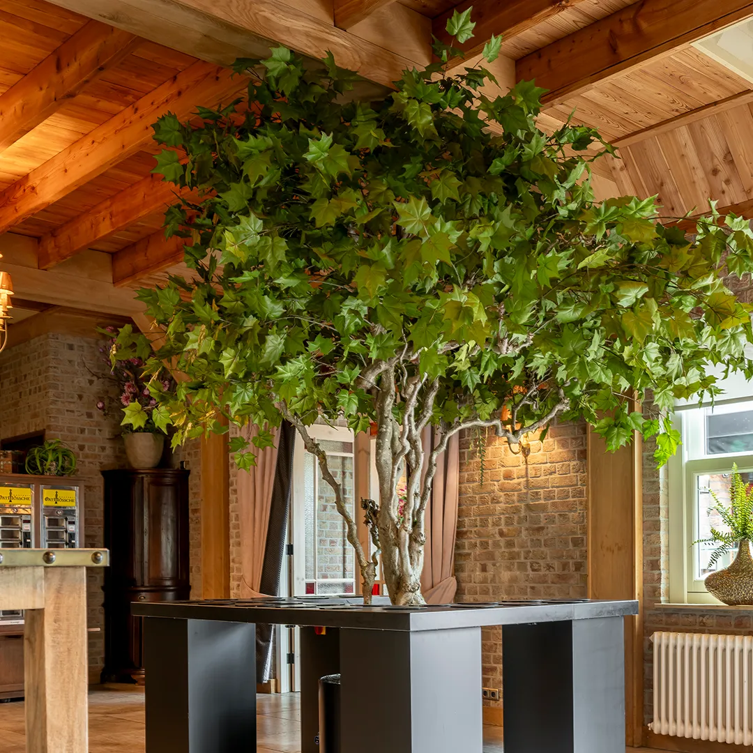 Maatwerk kunstboom op een centrale bartafel in een rustieke horecazaal, gerealiseerd door Miverde