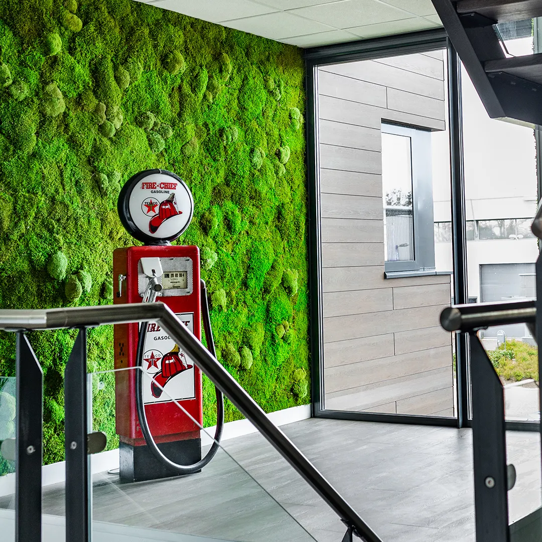 Grote groene bolmos moswand als sfeervolle achterwand naast een vintage Texaco benzinepomp in een kantooromgeving