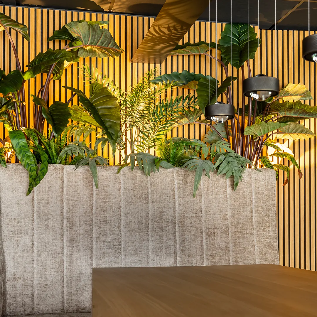 Luxe interieur met tropische planten in betonnen bakken voor gouden gestreepte wandpanelen en zwarte hanglampen