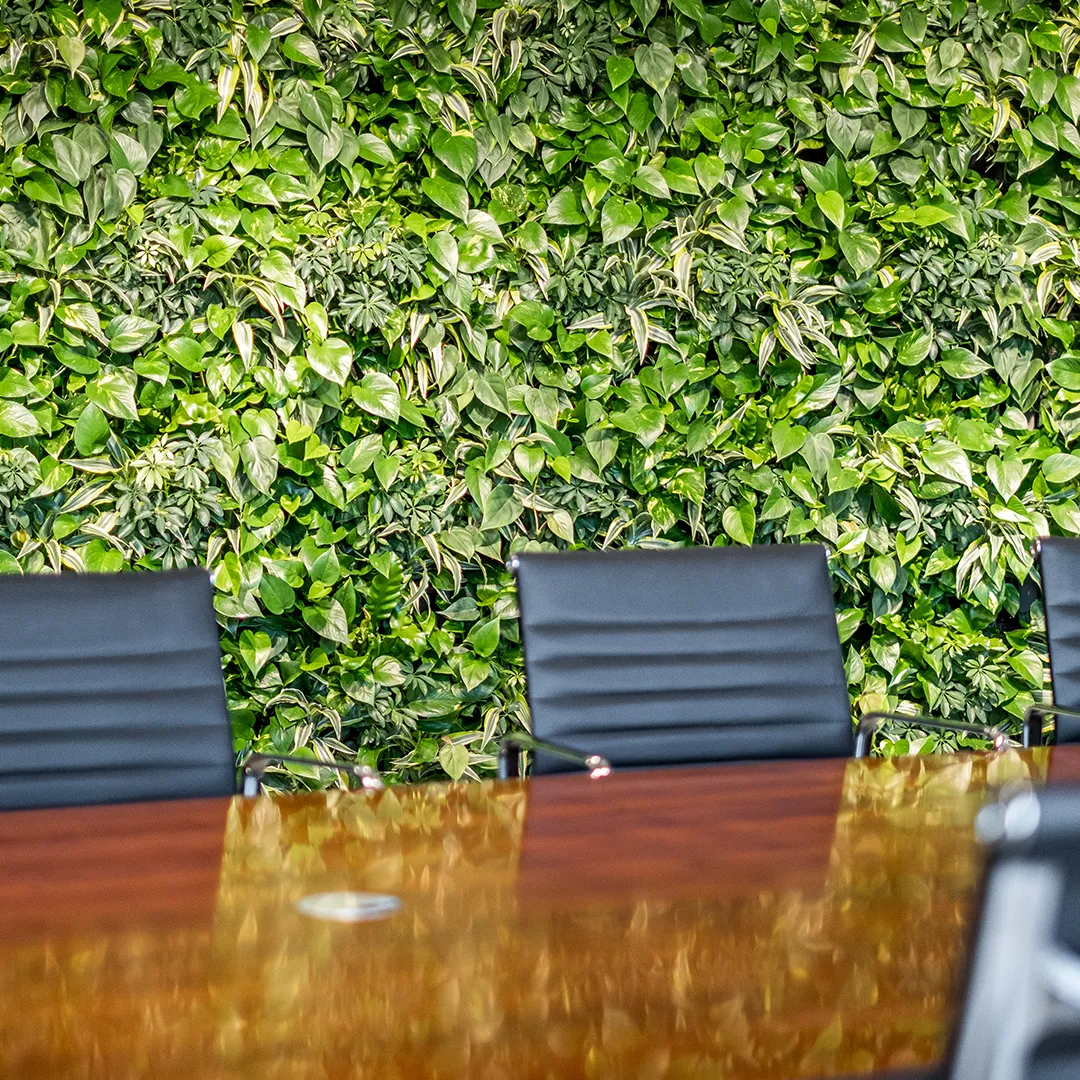 Luxe vergadertafel met zwarte stoelen voor levende groene plantenwand in modern kantoor