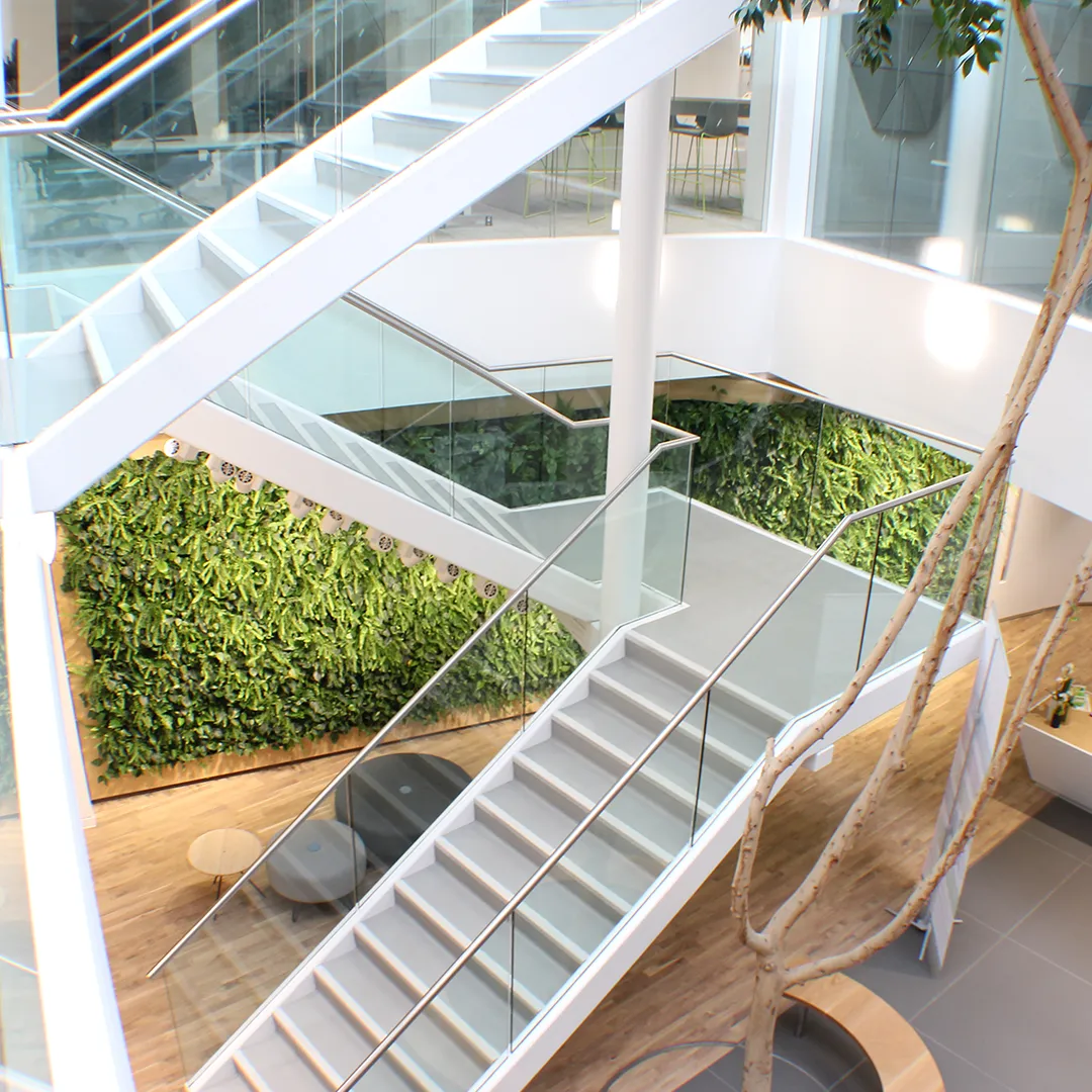 Witte designtrap met glazen wand en verticale groene plantenwand in modern kantoorpand