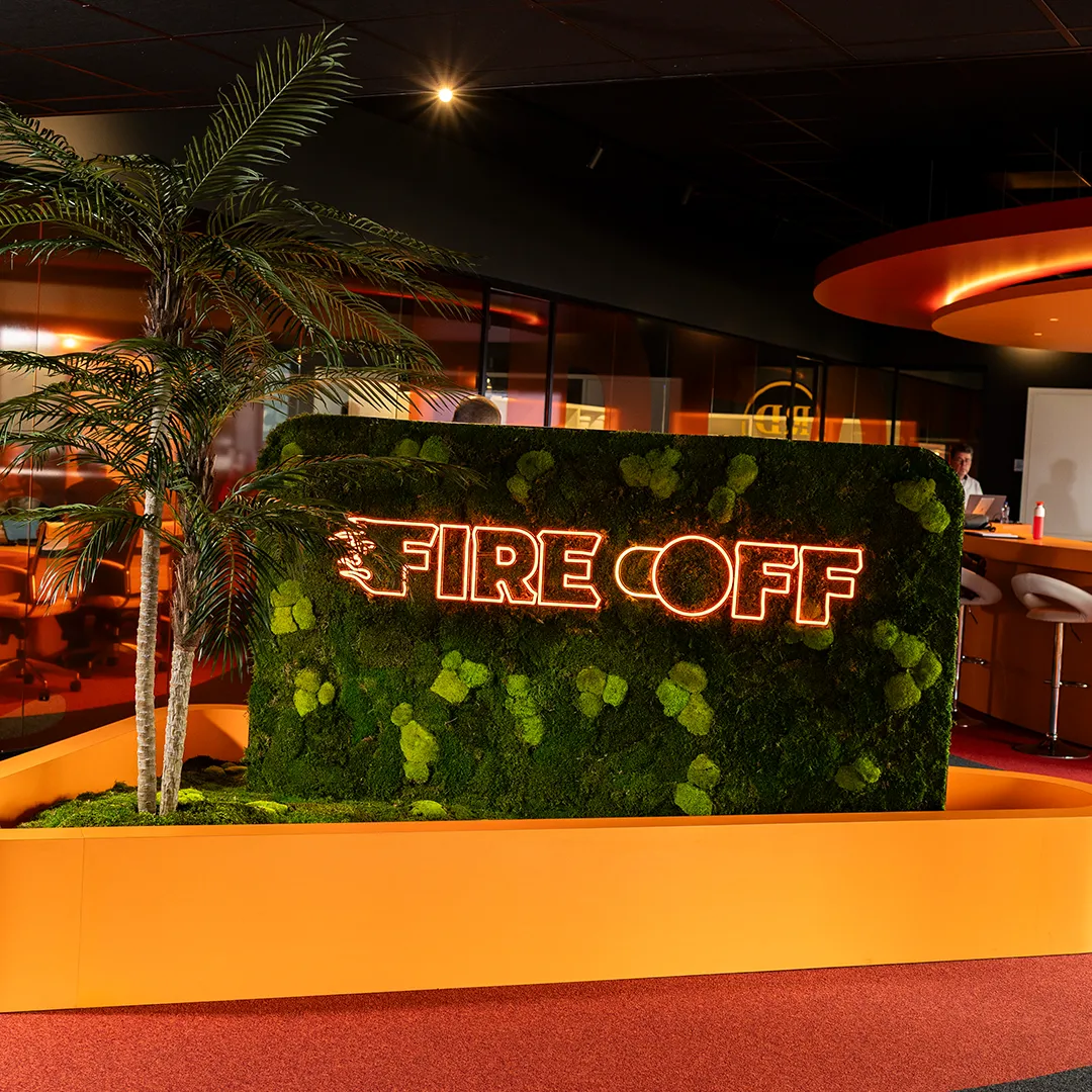 Fire Coff neon verlichting op groene moswand met palm in modern interieur met oranje accenten